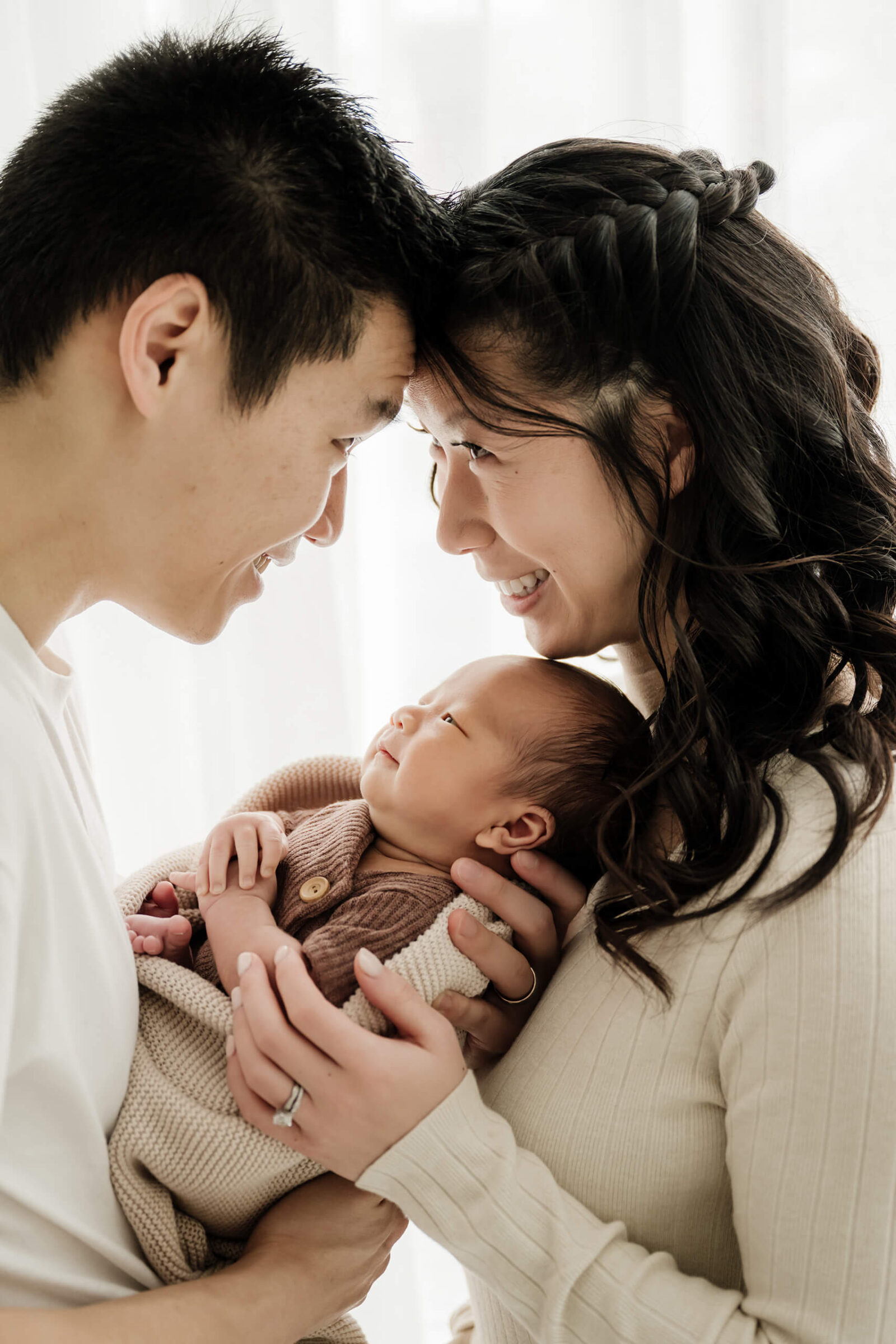 Parents holding their newborn baby close during a natural family newborn session in a Kirkland studio.