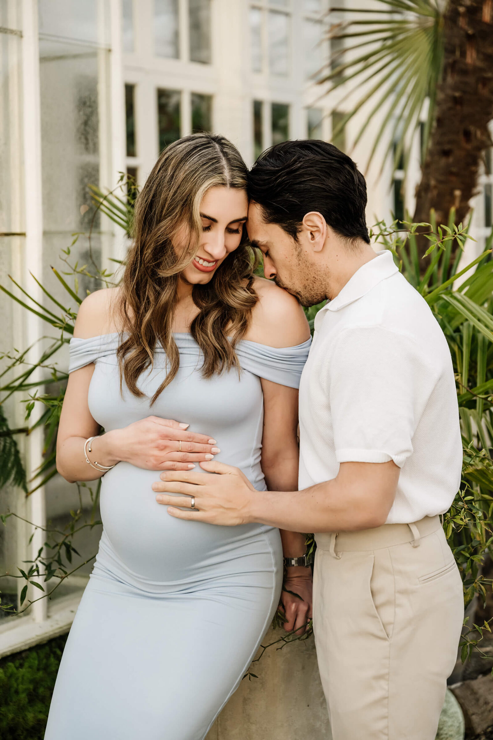 Expecting parents sharing a quiet moment in a garden setting during a natural outdoor maternity session.