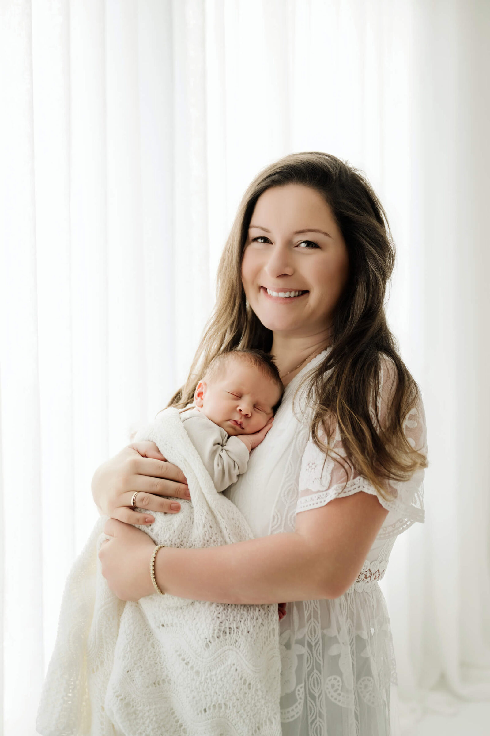 Mom holding her sleeping newborn baby in a soft studio portrait, part of a maternity and newborn photography package.