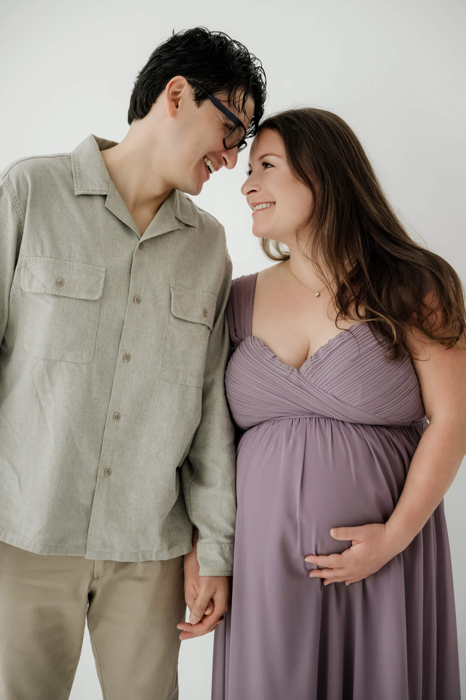 Expecting parents smiling together during a natural studio maternity session.
