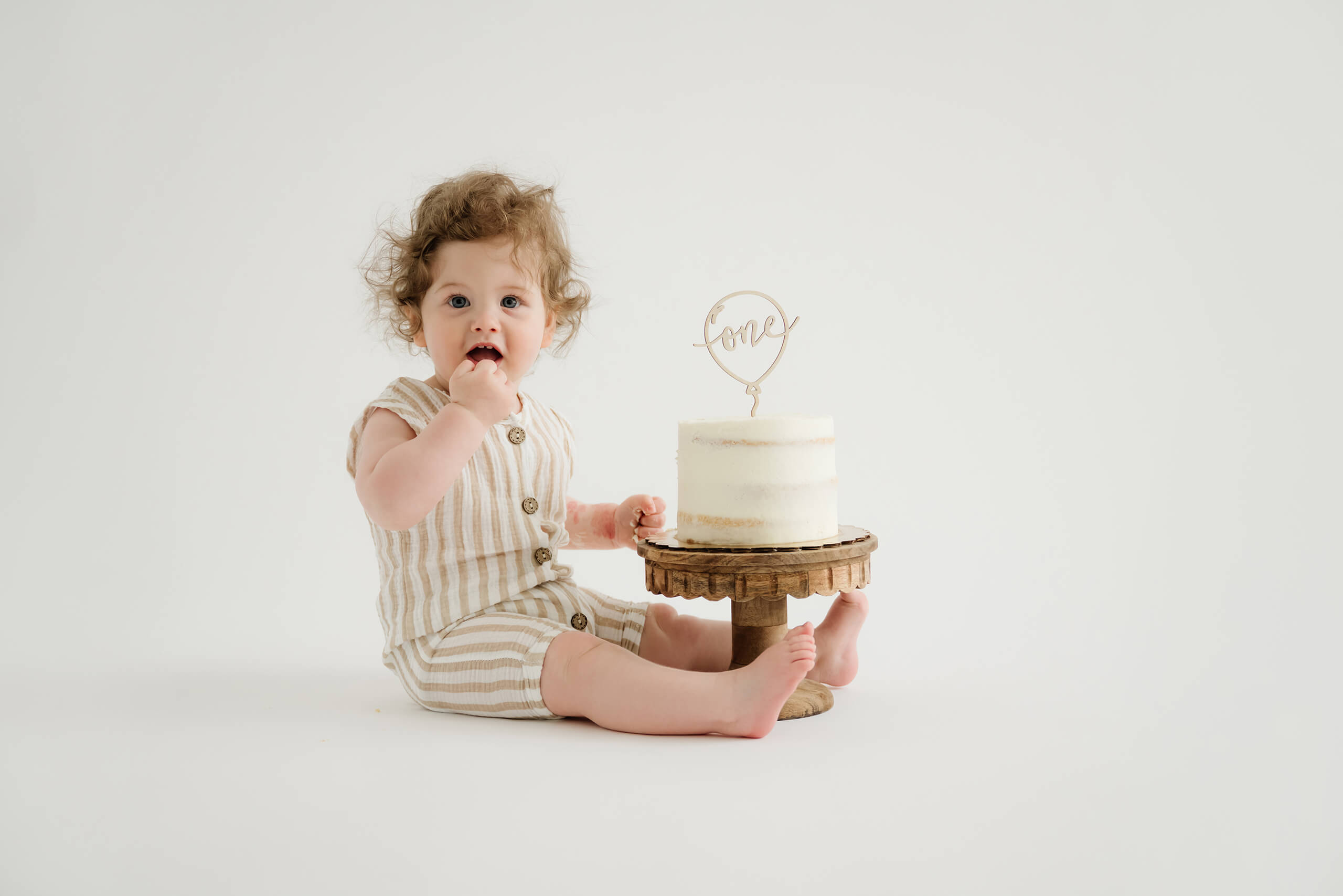 One-year-old enjoying a cake smash session in a bright photography studio near Bellevue.