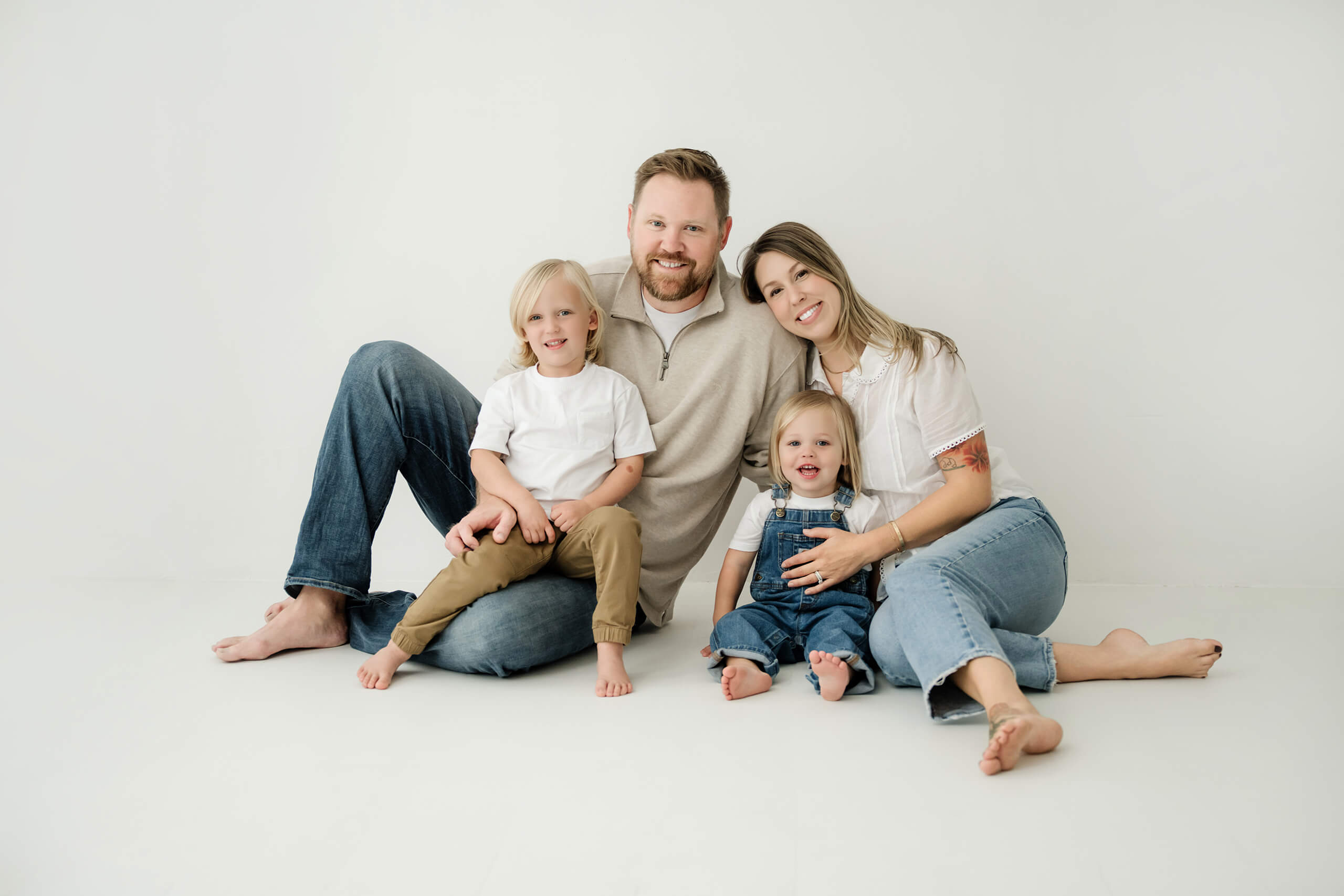 Family of four sitting together for a relaxed studio family portrait near Bellevue.