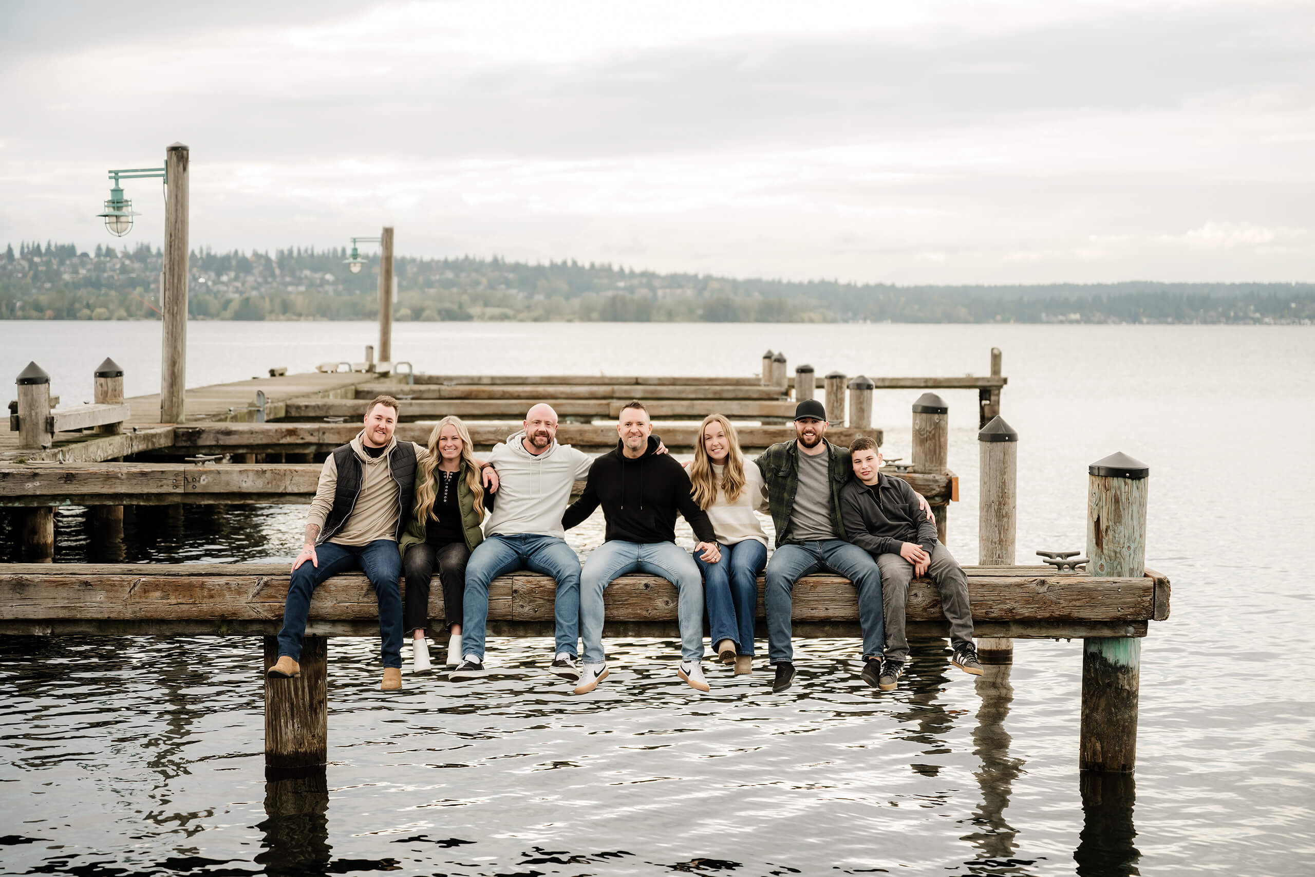 Extended family sitting together on a wooden dock during a Bellevue family photography session by the water.