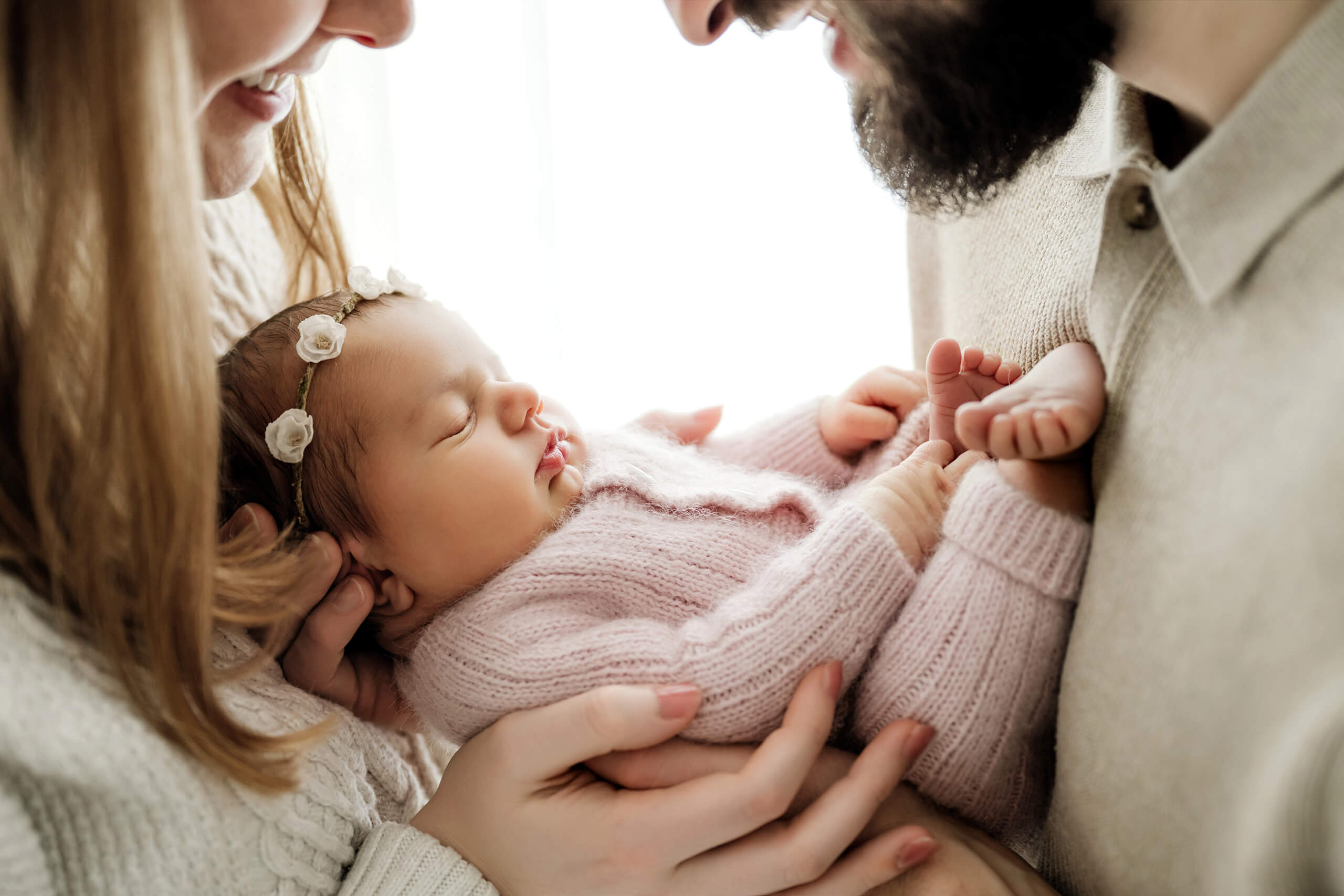 Parents holding their sleeping newborn close during a soft newborn portrait.