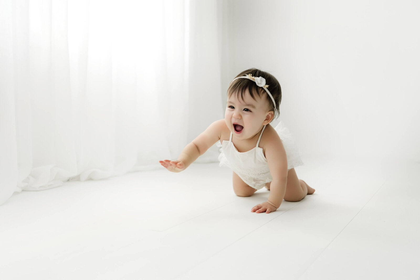 Baby crawling across a bright white studio during a Mercer Island milestone photography session.