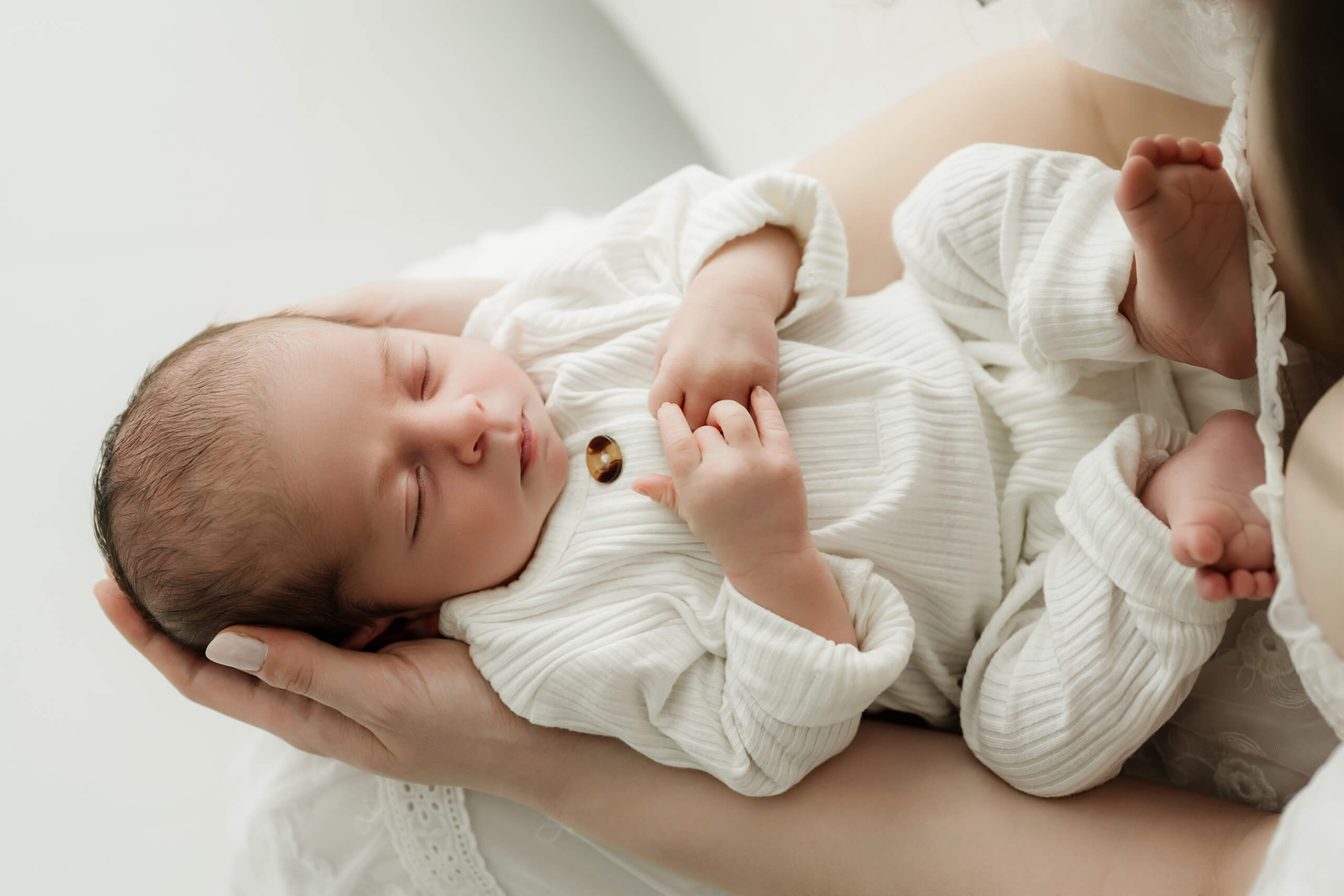 Sleeping newborn resting in a parent’s hands during a soft Mercer Island newborn photography session.