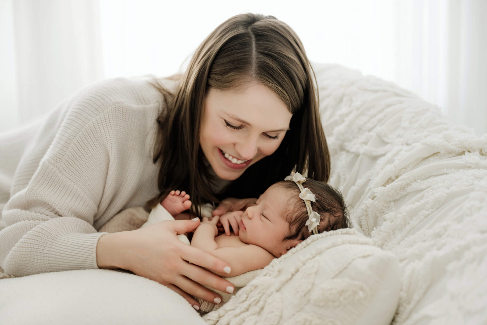 Mother smiling at her sleeping newborn during a soft Mercer Island newborn photography session.