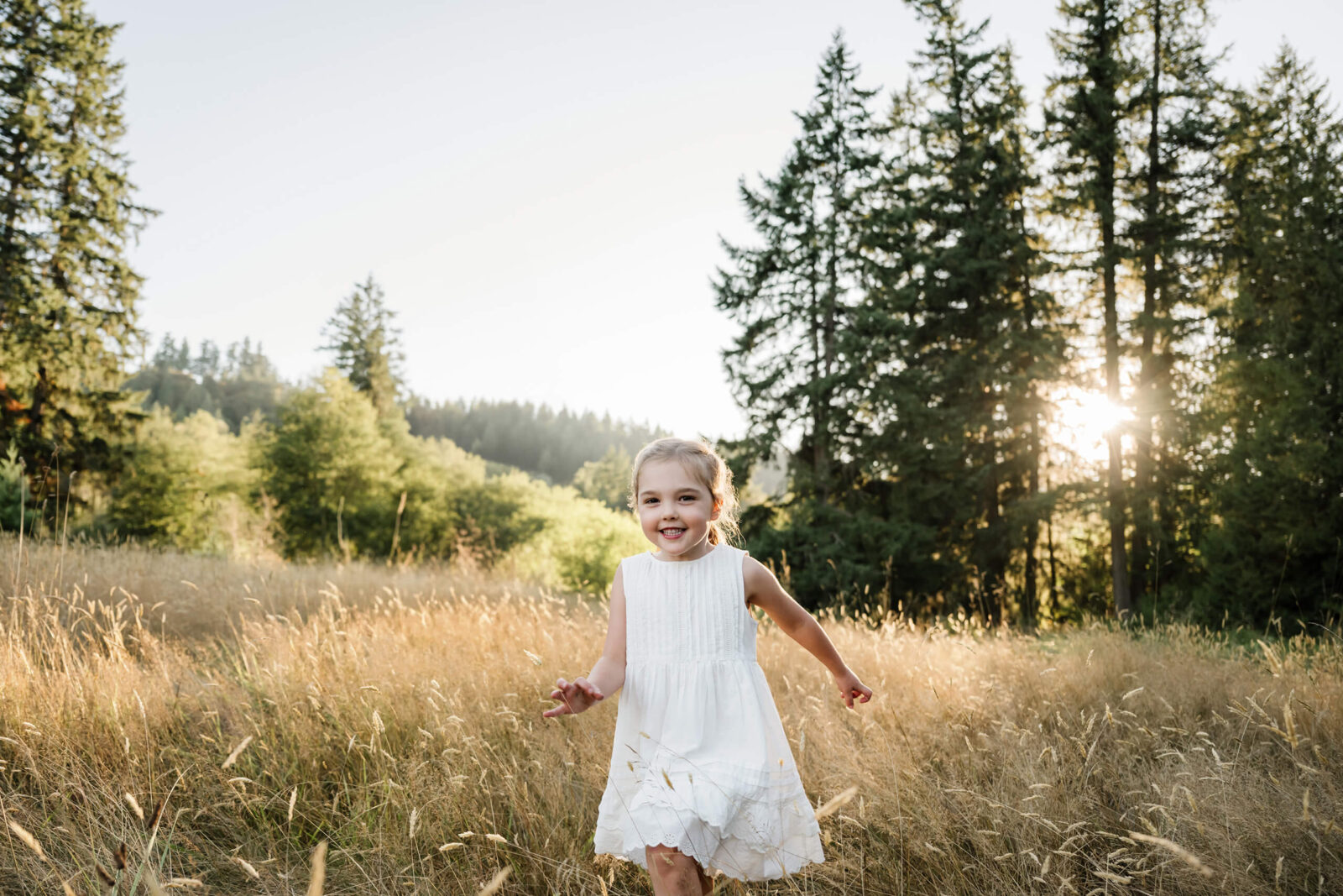 Smiling young girl standing in tall golden grass during a Redmond family photography session.