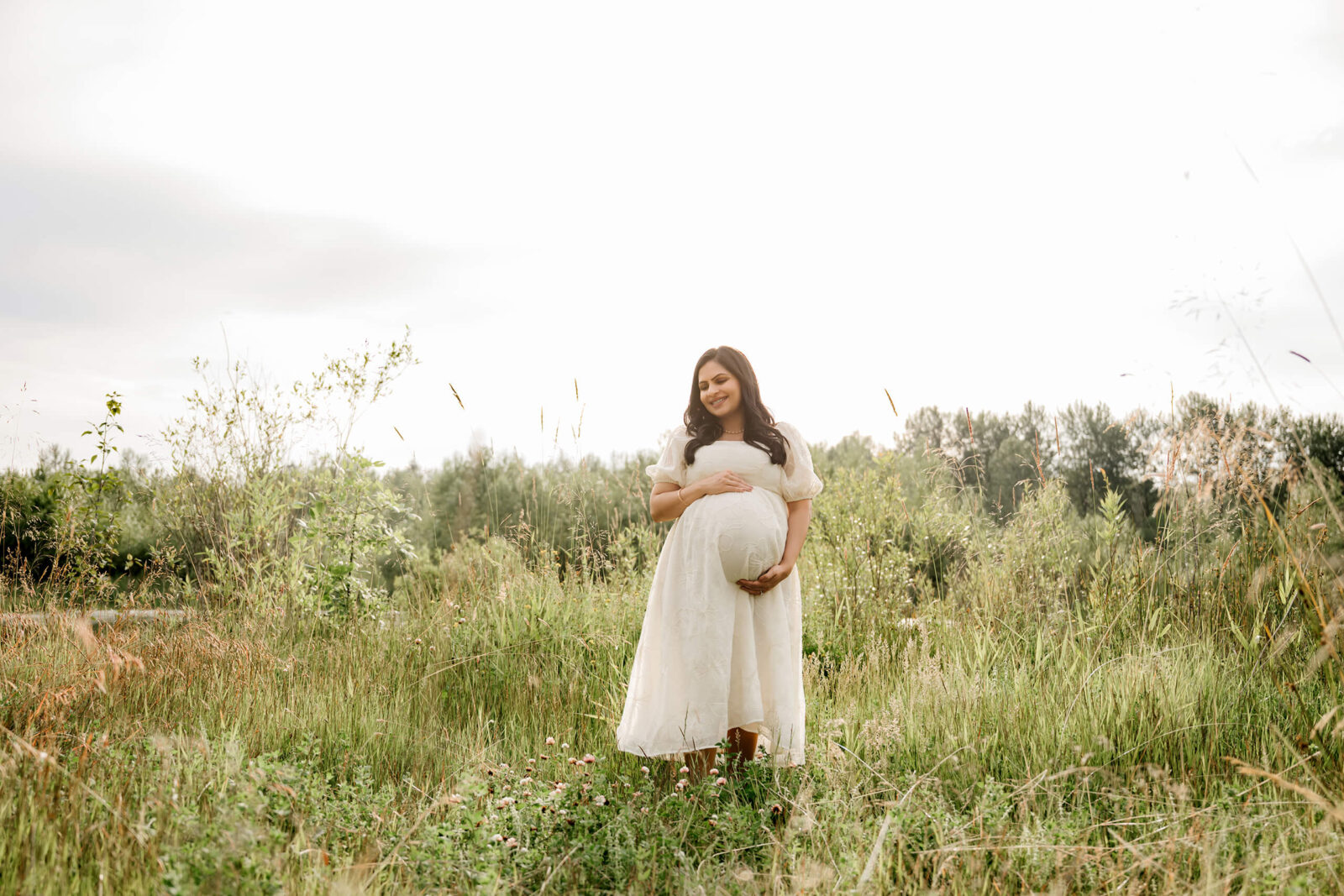 Pregnant mother standing in a tall grassy field during a Redmond maternity photography session.