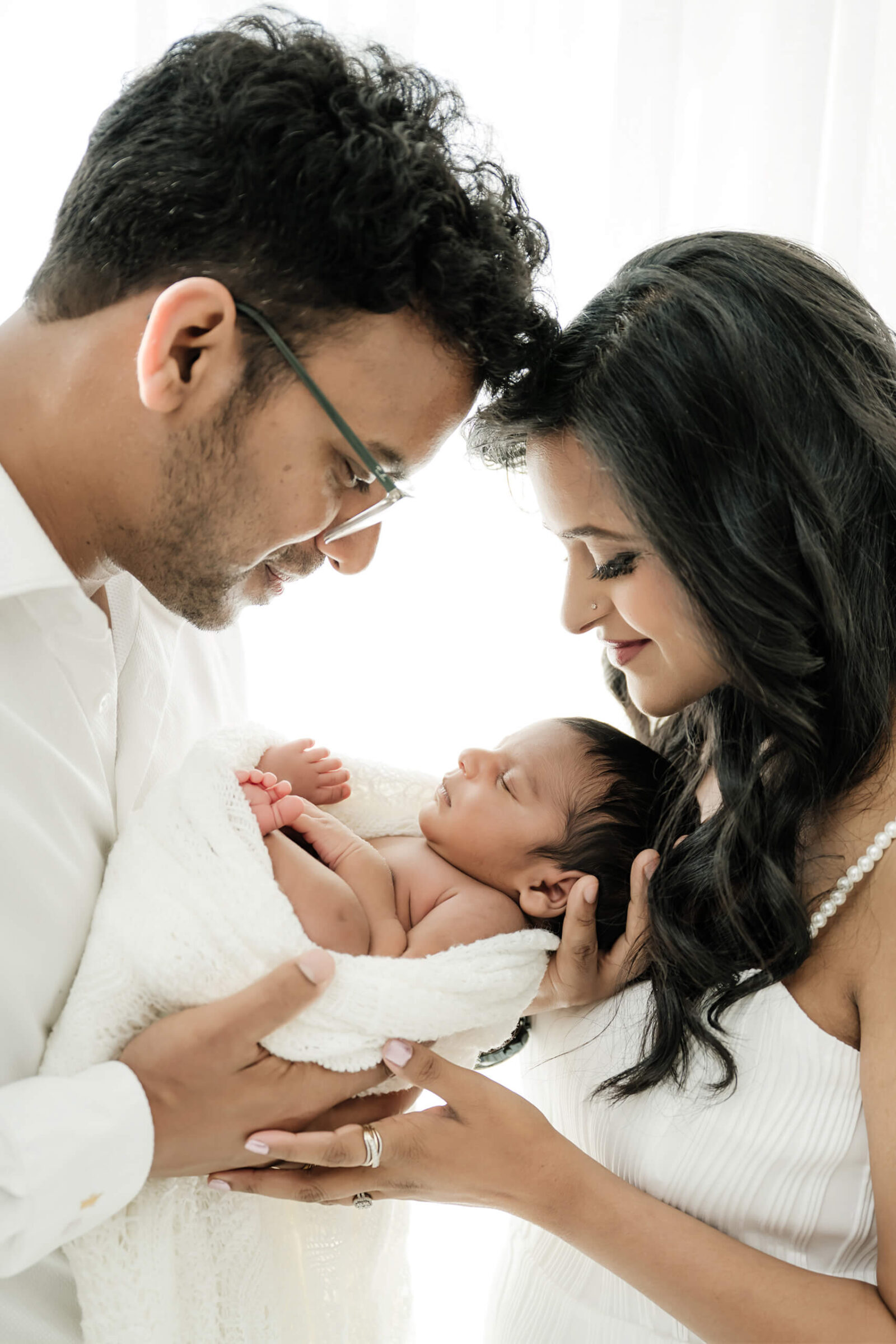 Parents smiling down at their sleeping newborn during a Redmond newborn photography session.