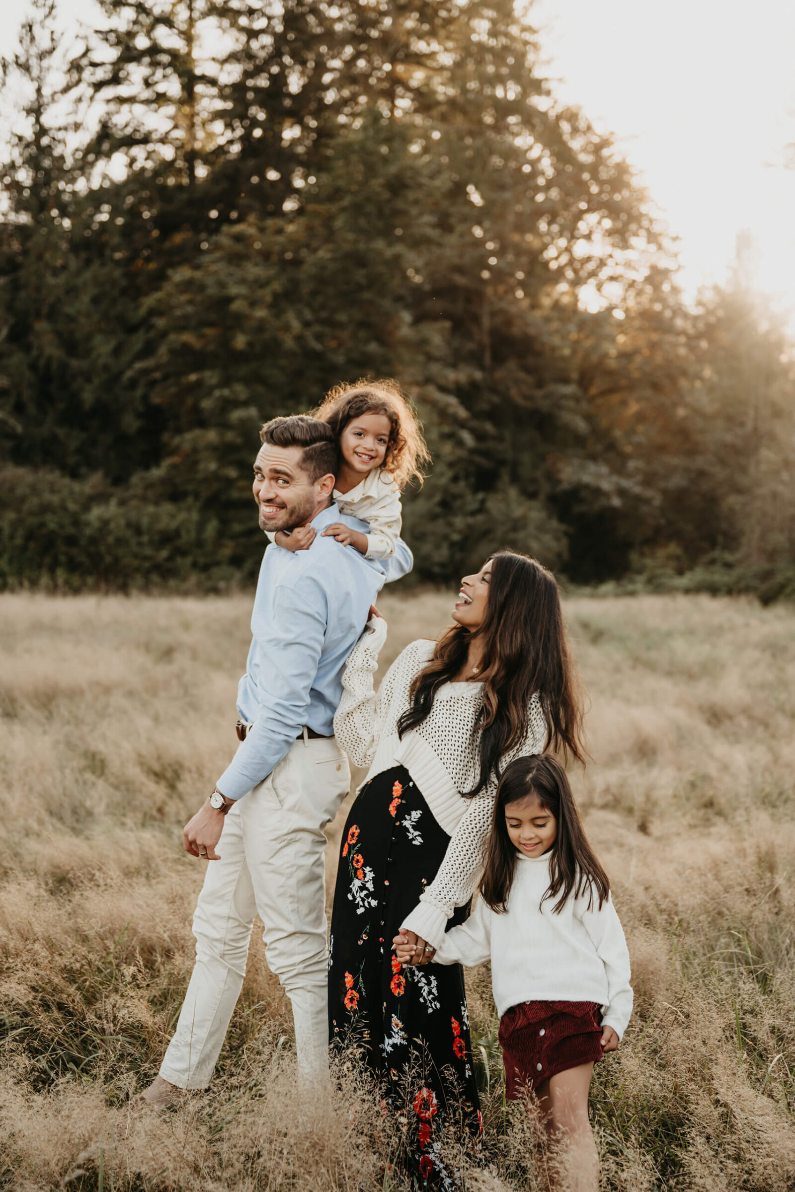 Family of four walking through tall grass at sunset during a Sammamish family photography session.