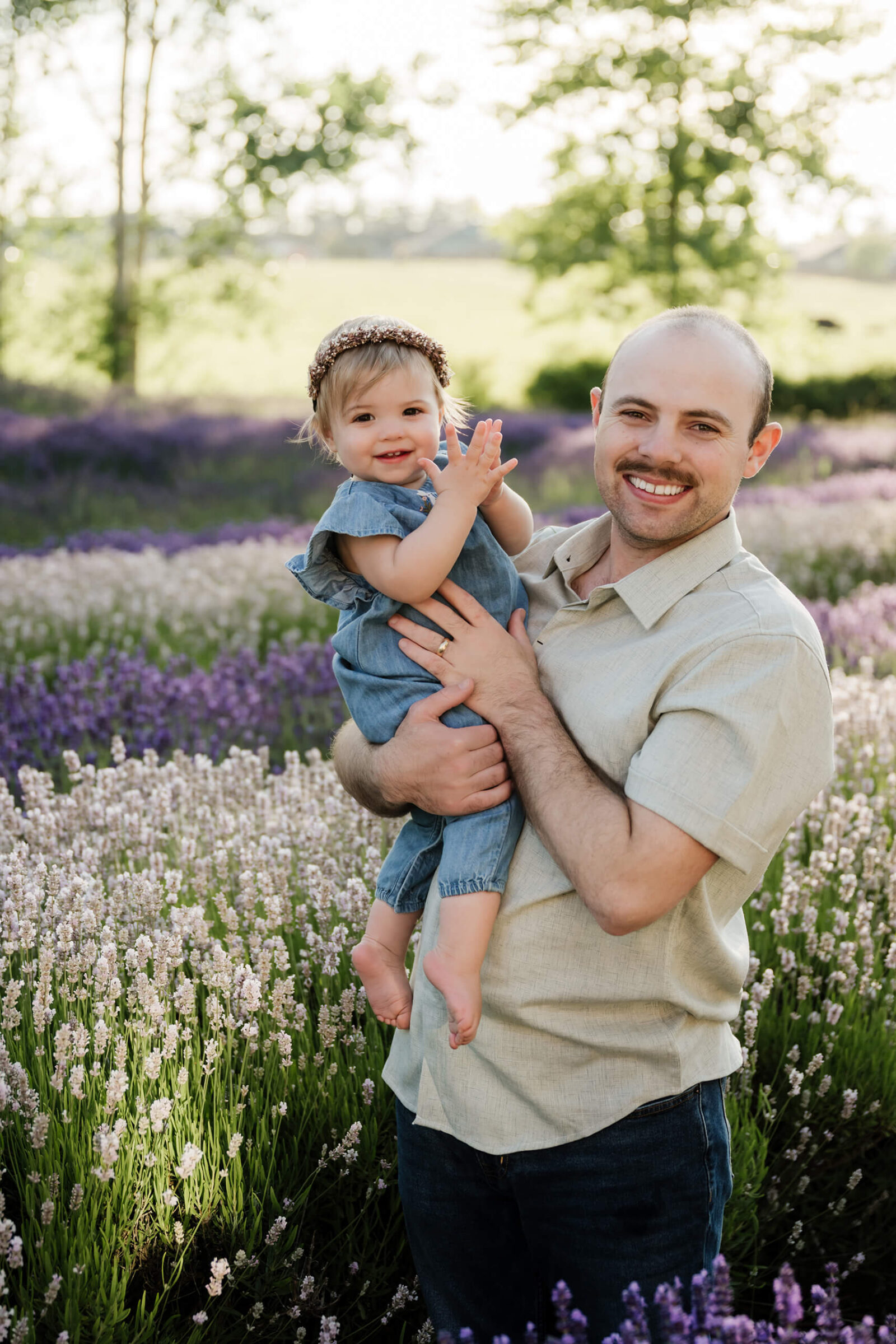 Dad holding his young daughter among lavender blooms during a Seattle-area family photography session.