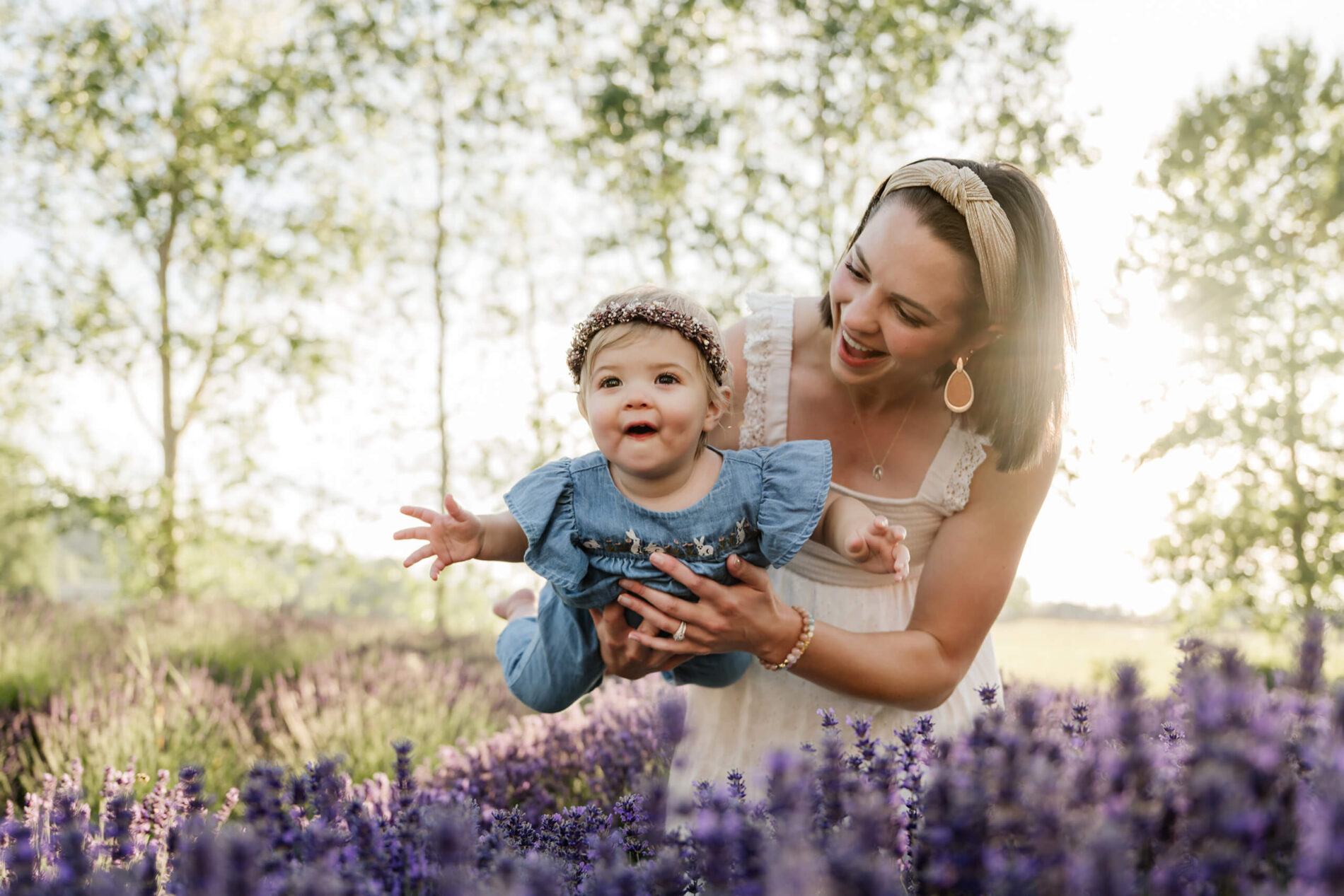 Mom playfully lifting her toddler above the lavender during a joyful family session at the farm.