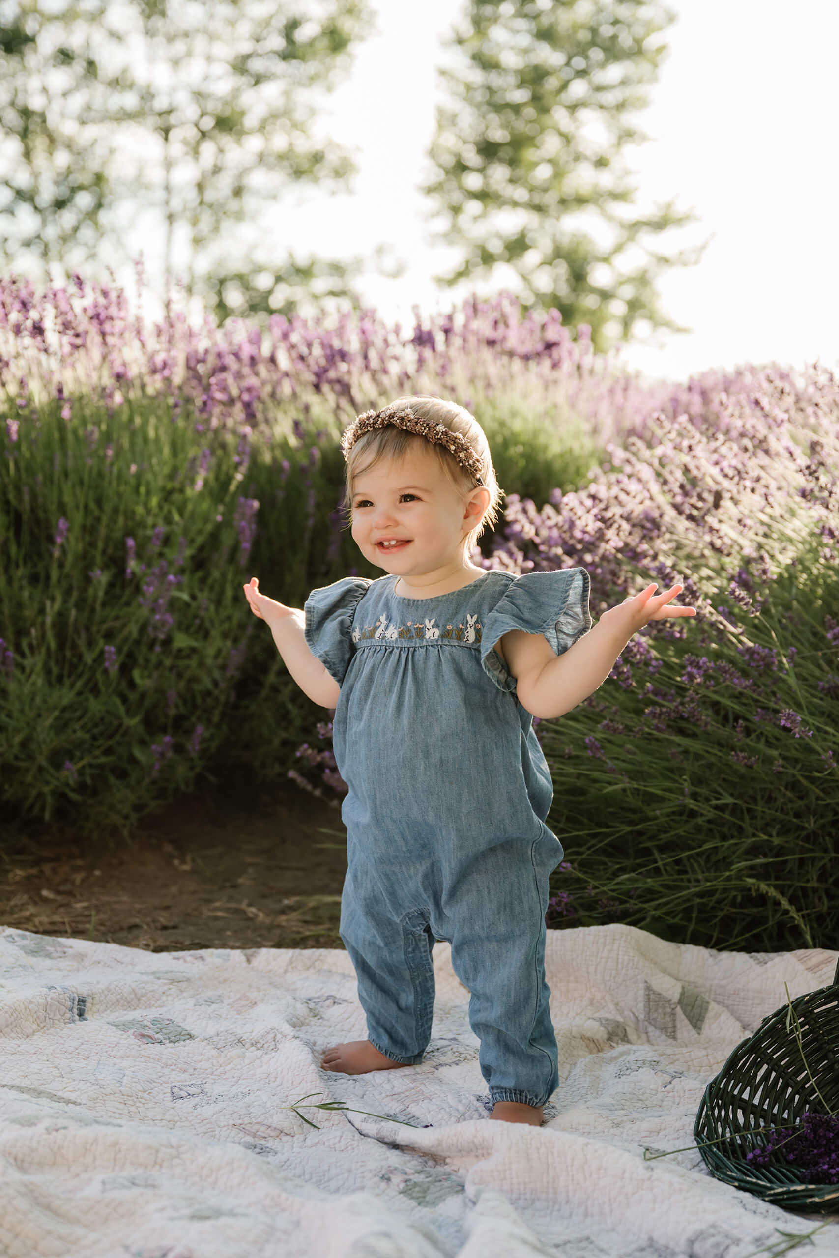 Young child standing on a quilt between lavender rows during a summer family photo session.