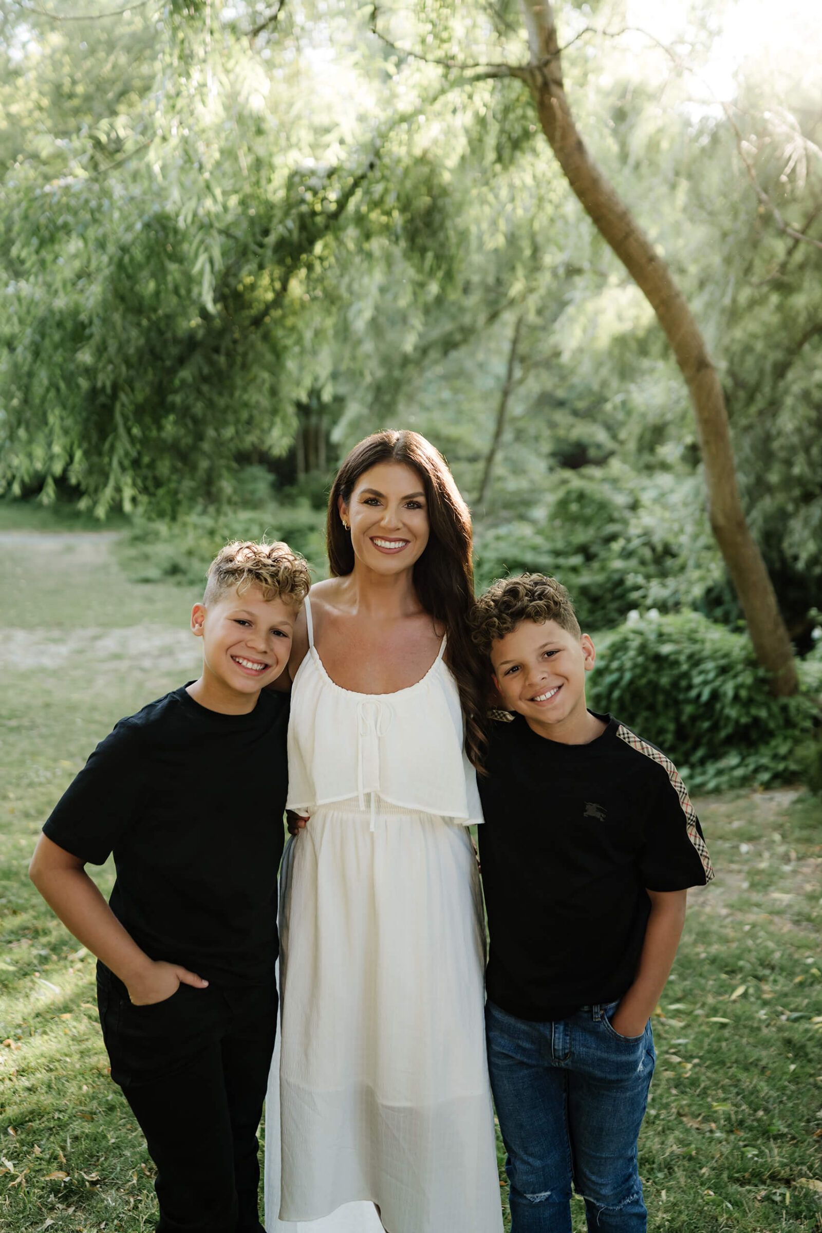 Mom standing with her two sons in a green park during a Seattle family photo session.