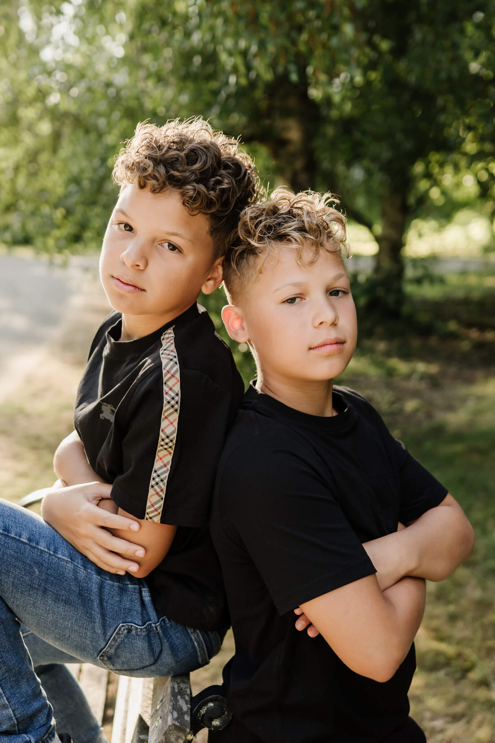 Two brothers sitting back to back outdoors during a family photography session.