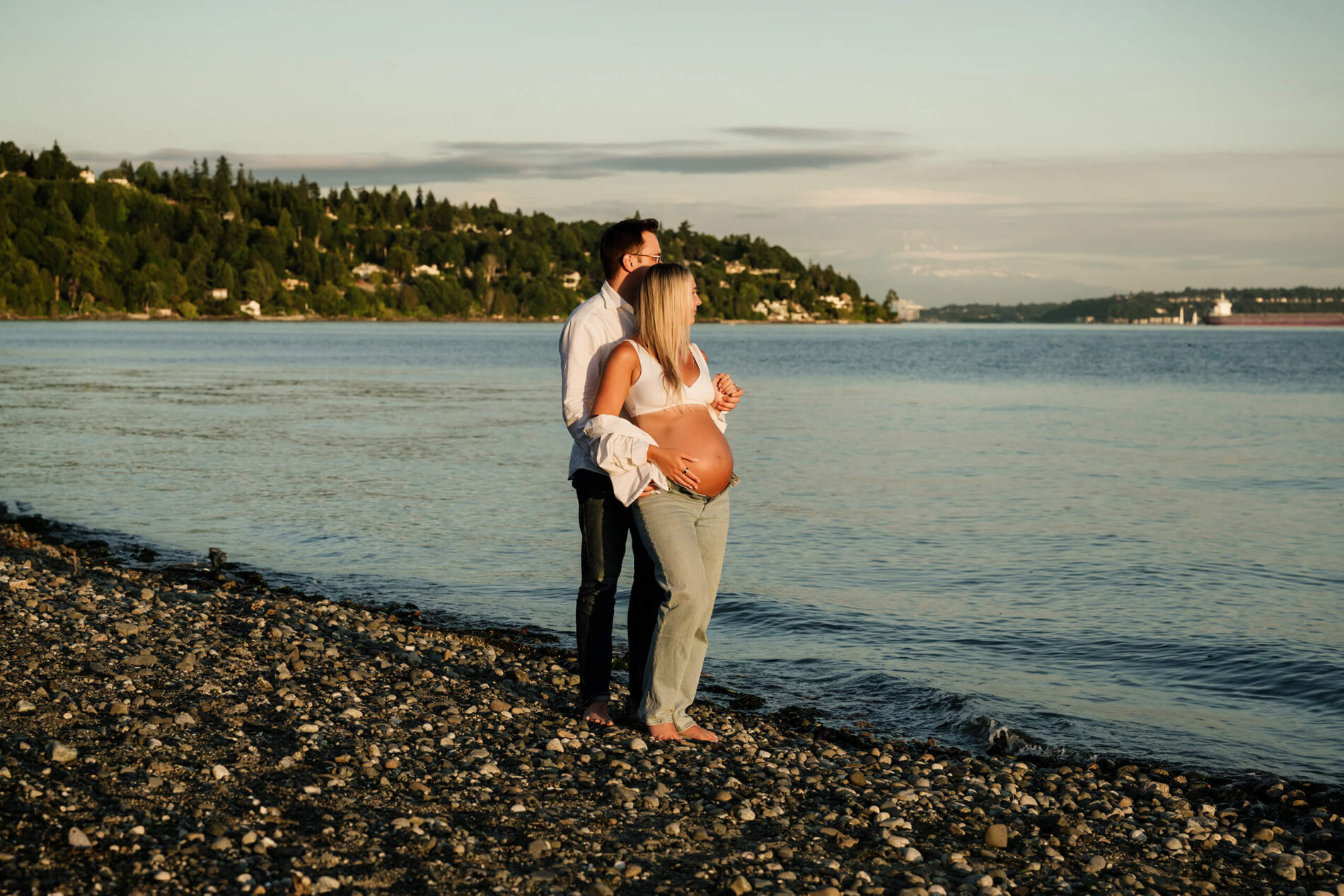 Pregnant couple overlooking Puget Sound during a golden-hour maternity session on the beach.