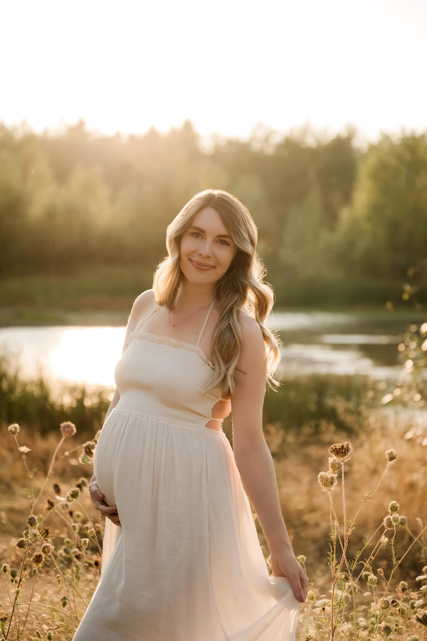 Pregnant woman holding her belly near the water at sunset during a Seattle maternity session.