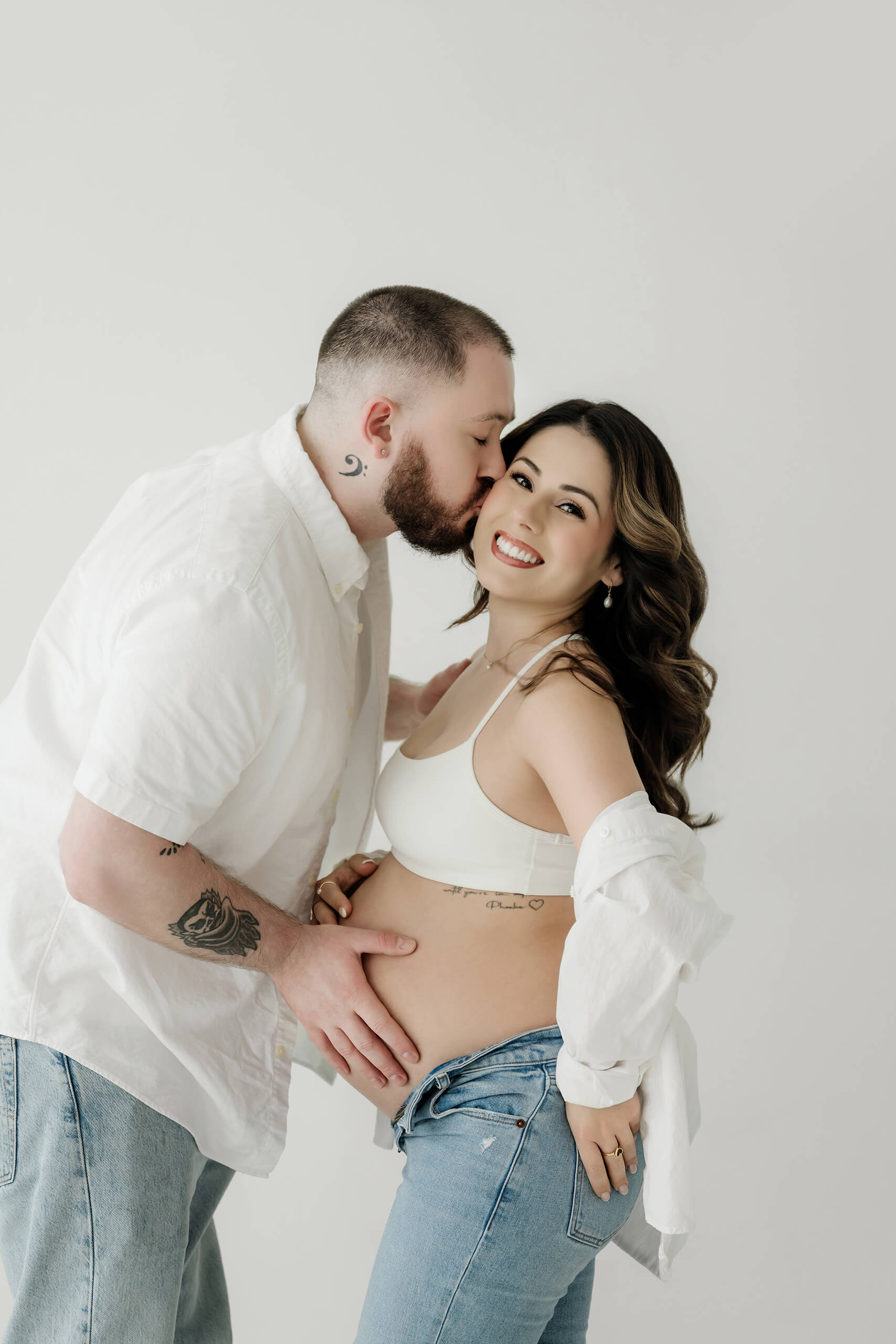 Expecting couple sharing a close moment with one hand resting on the baby bump.