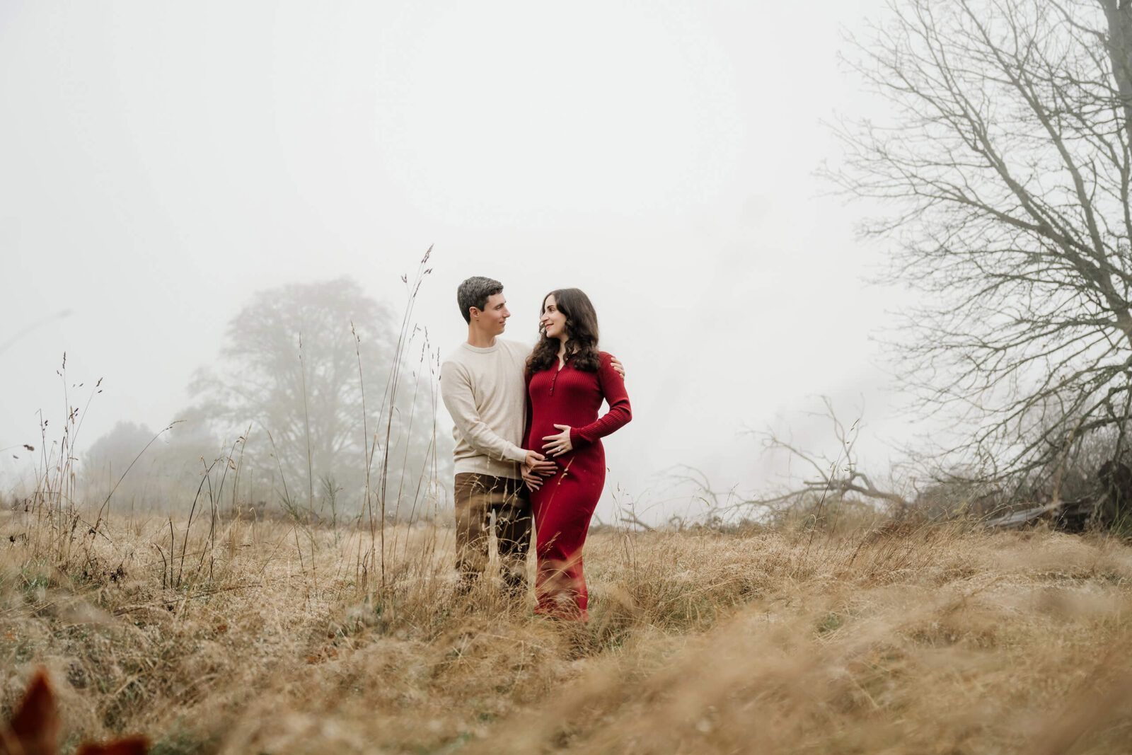 Expecting couple standing in a foggy winter field during an outdoor maternity session.