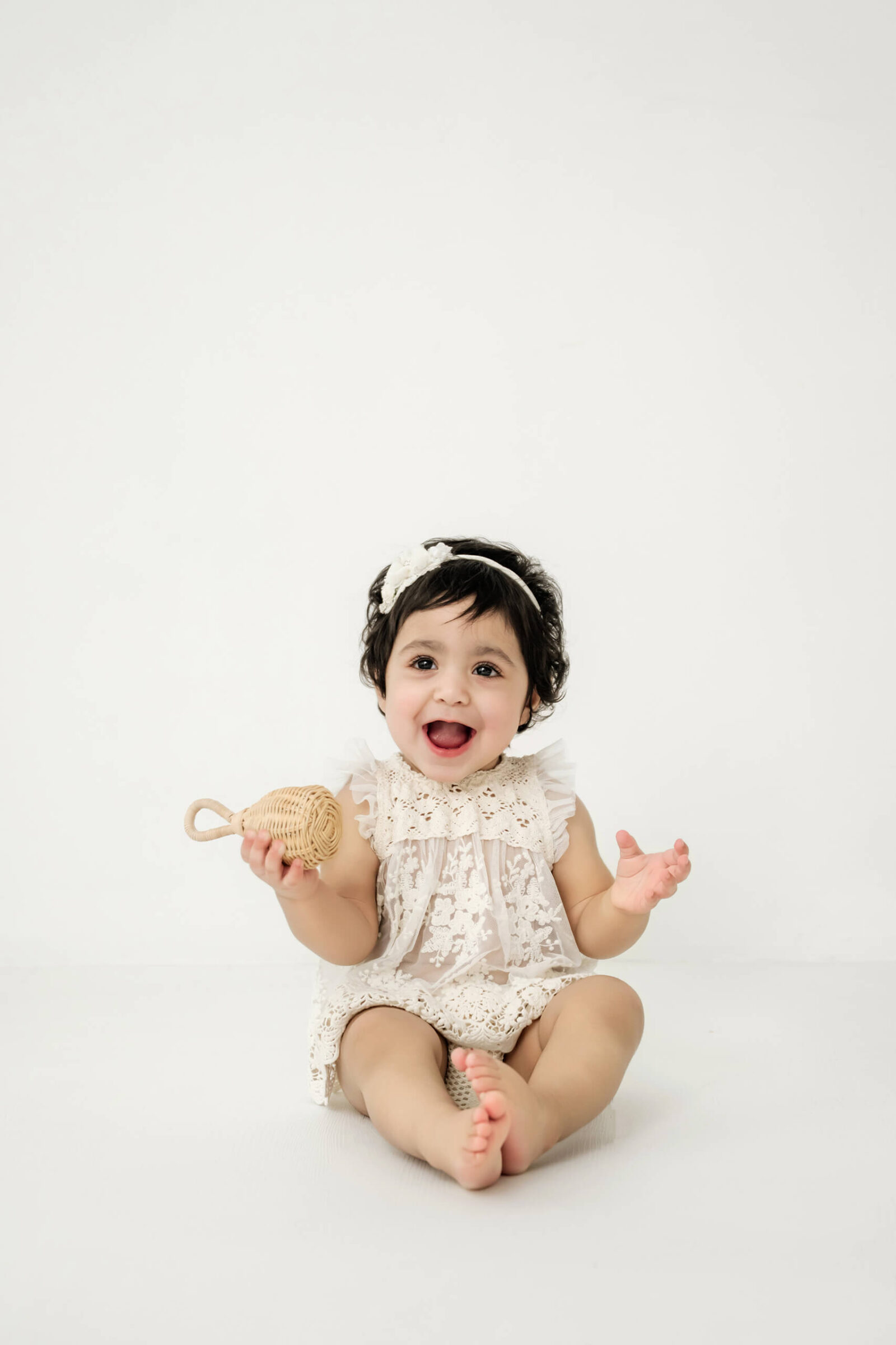 Baby girl smiling with a toy during a first birthday milestone photo session at Lana Sky Photography's Kirkland studio near Seattle.