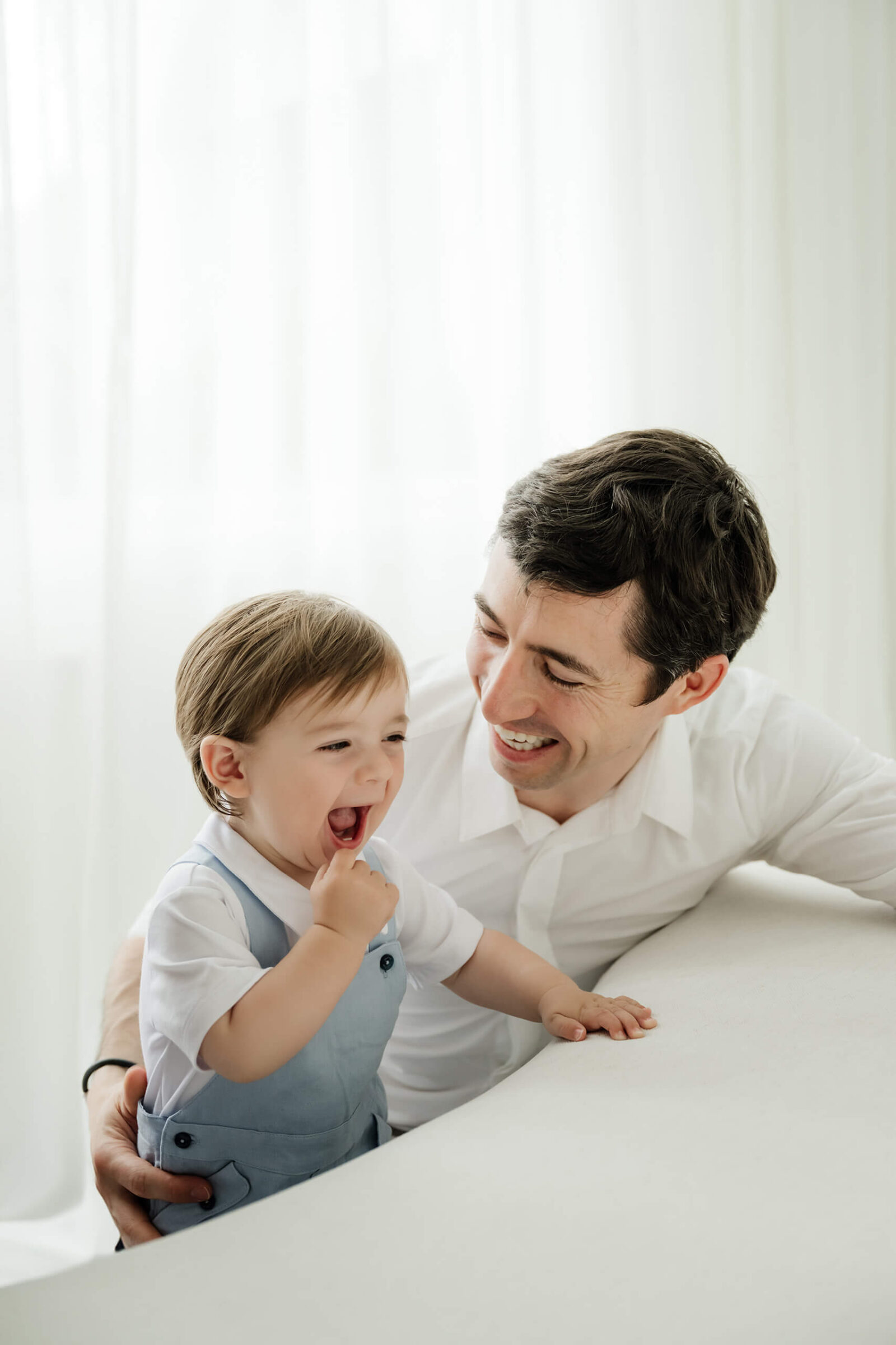 Dad laughing with his one-year-old son during a Seattle first birthday milestone family photography session.