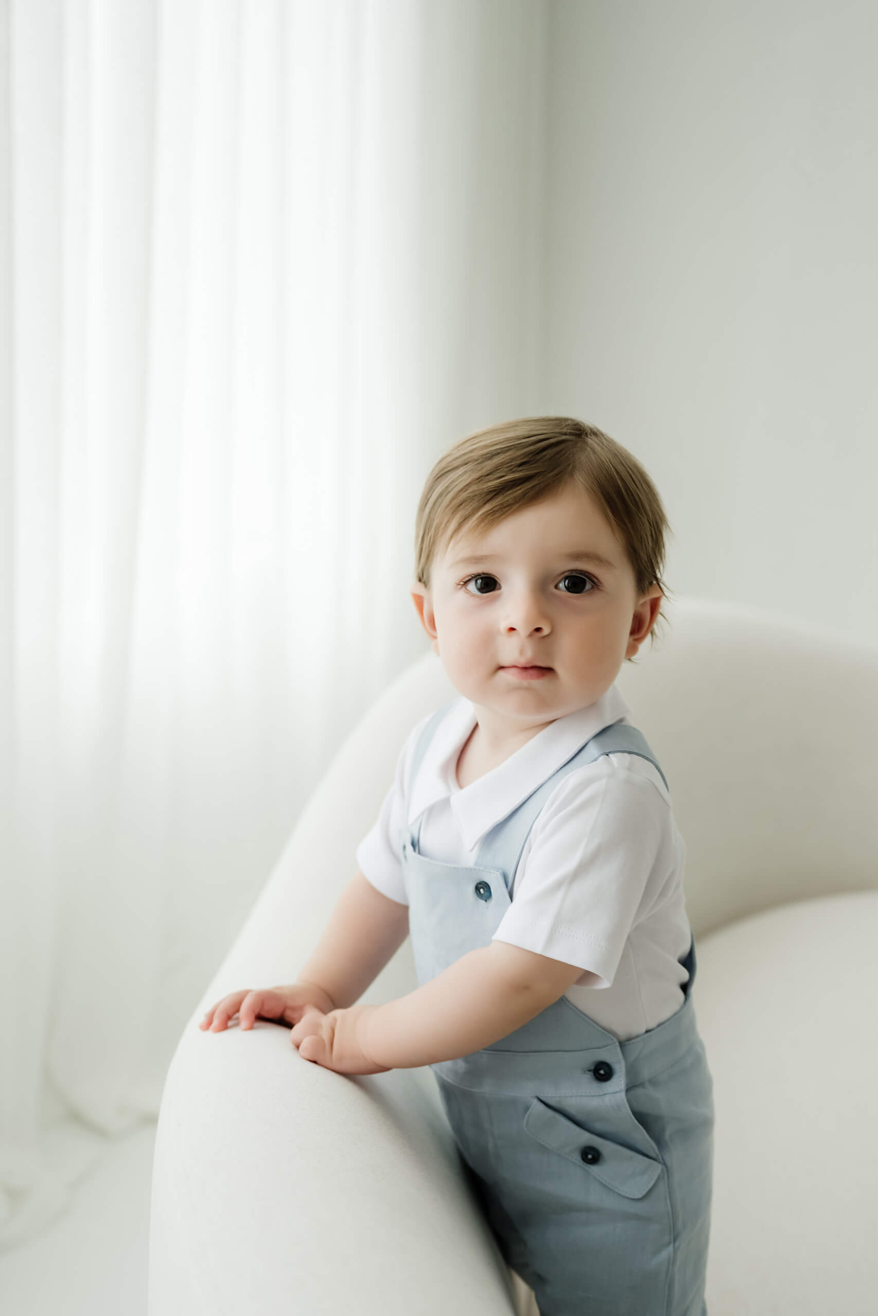 One-year-old boy in blue overalls during a simple first birthday milestone photo session at Lana Sky Photography’s Kirkland studio.