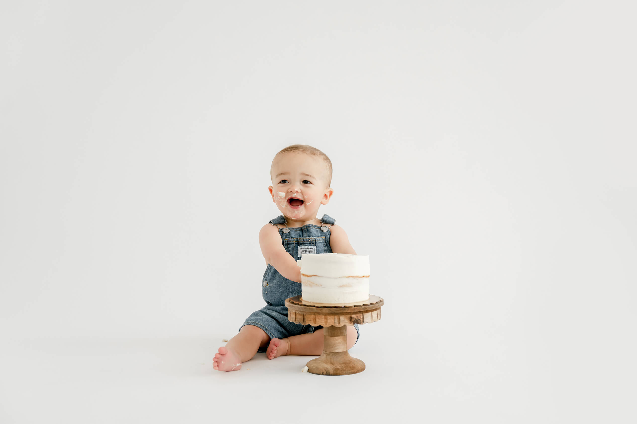 One-year-old boy smiling with his birthday cake during a Seattle cake smash photography session at Lana Sky Photography’s Kirkland studio.