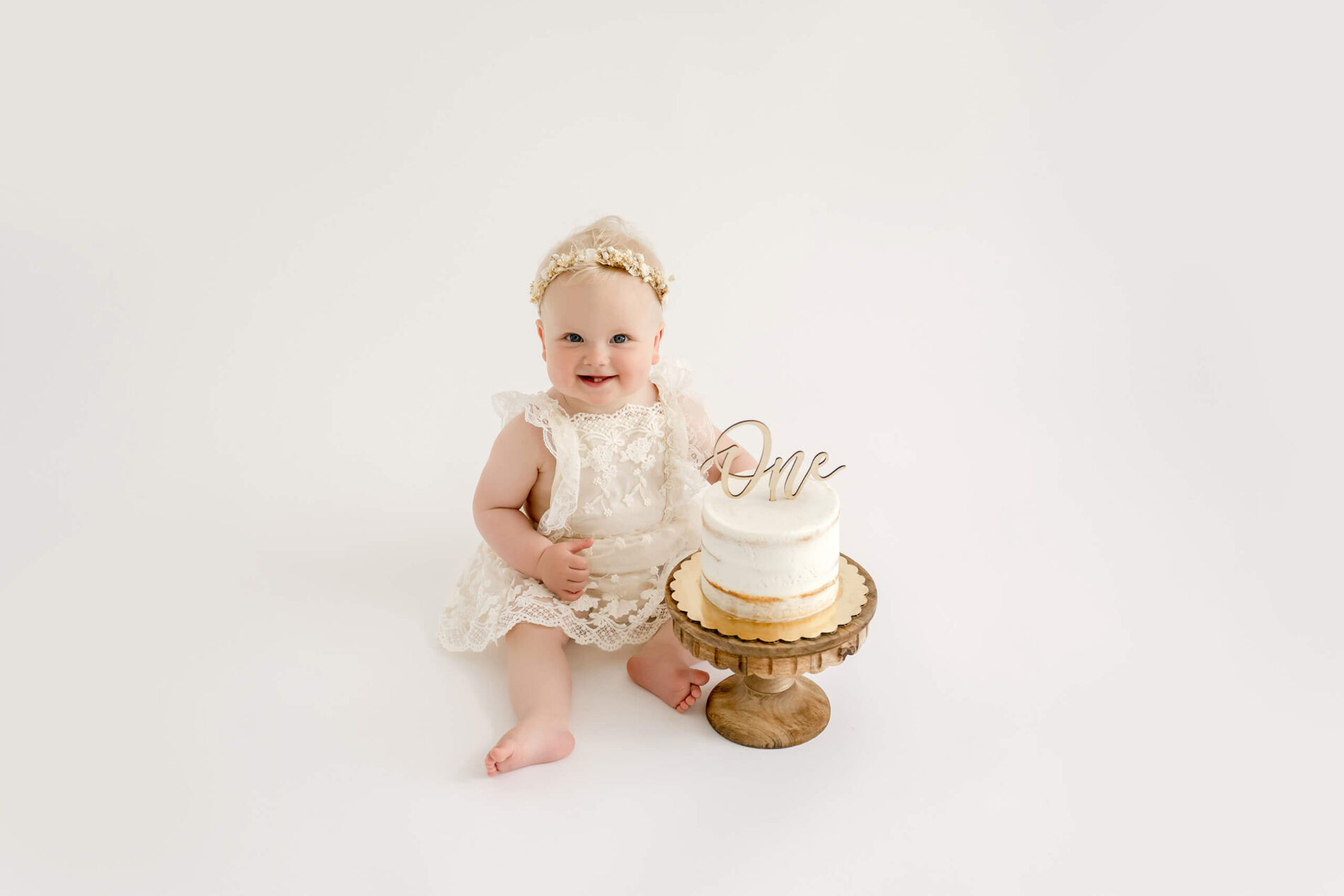 Baby girl sitting beside her first birthday cake during a Seattle cake smash photography session at Lana Sky Photography’s Kirkland studio.