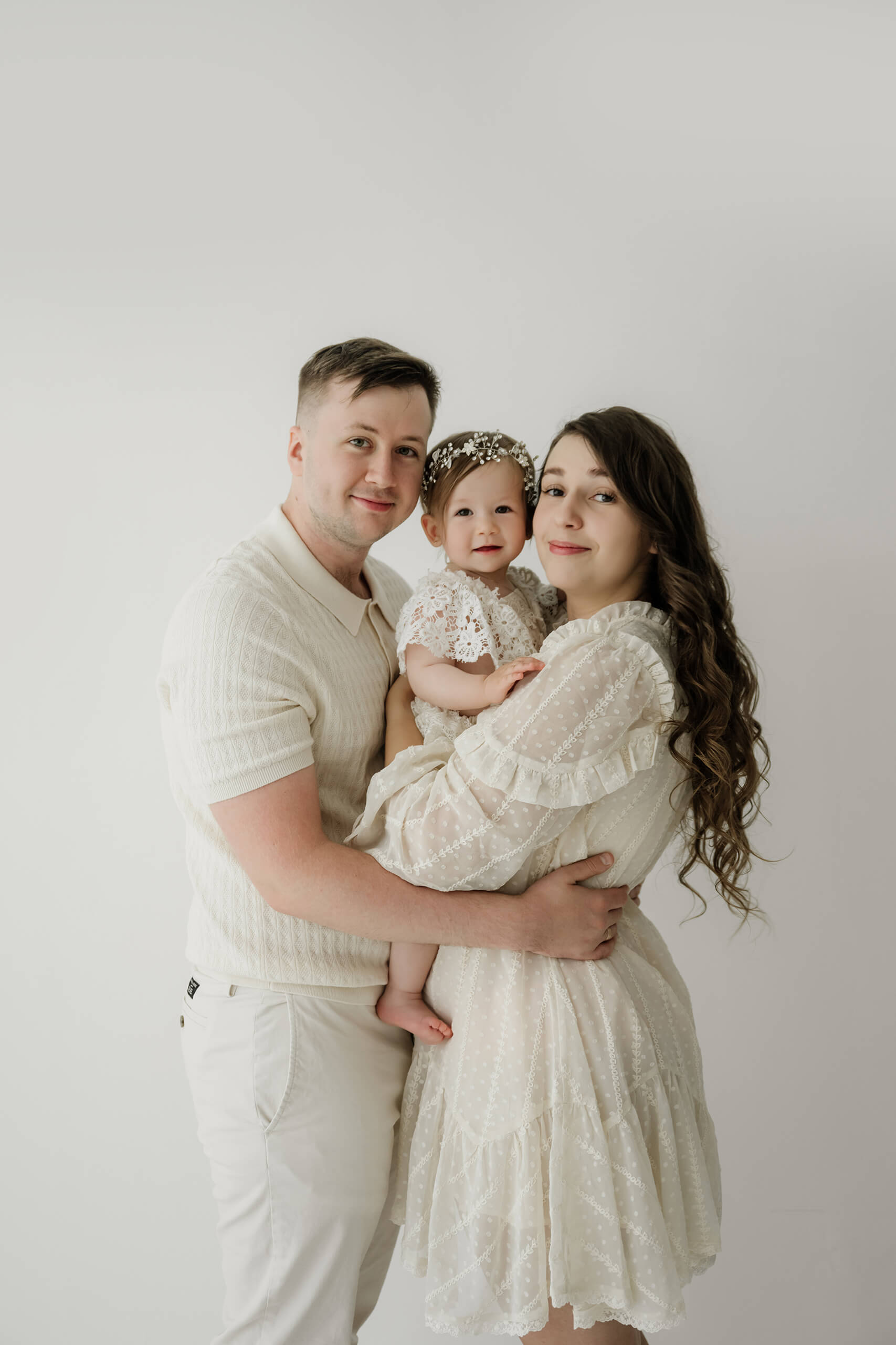 Mom and dad holding their one-year-old daughter during a Seattle first birthday milestone photography session.