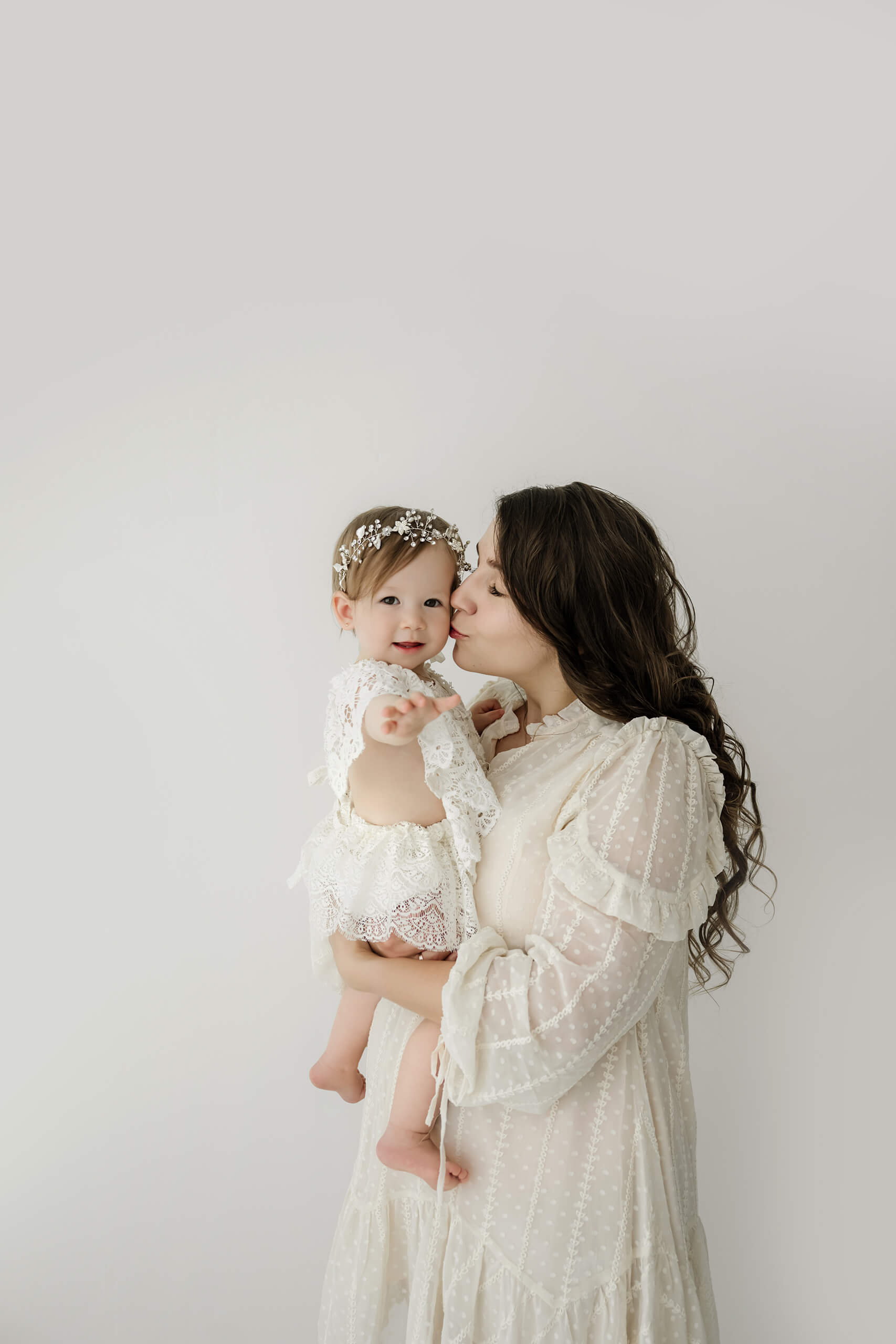 Mother kissing her one-year-old daughter during a first birthday milestone portrait session near Seattle.