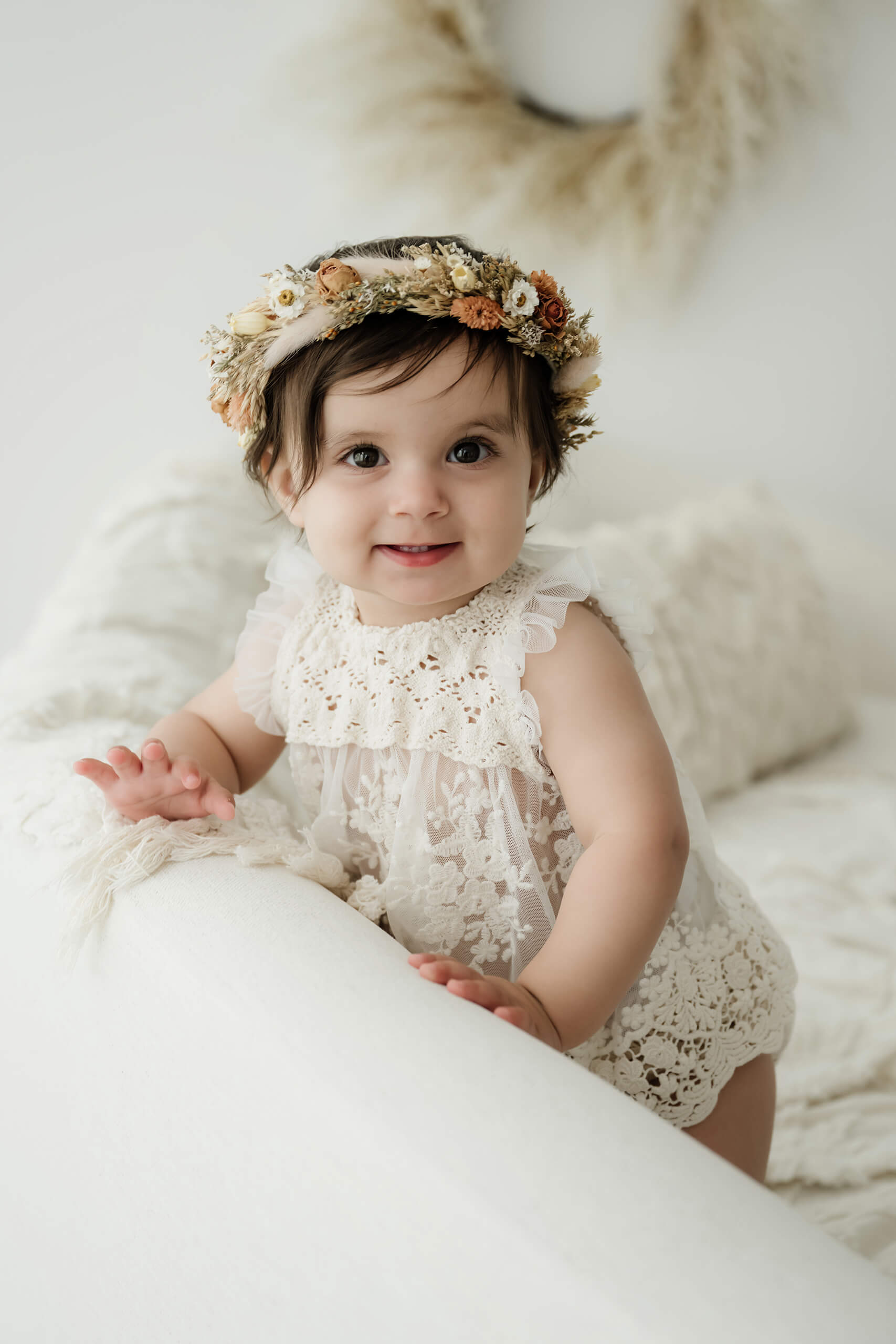 Smiling baby girl in a white lace outfit during a first birthday milestone portrait session in Kirkland.