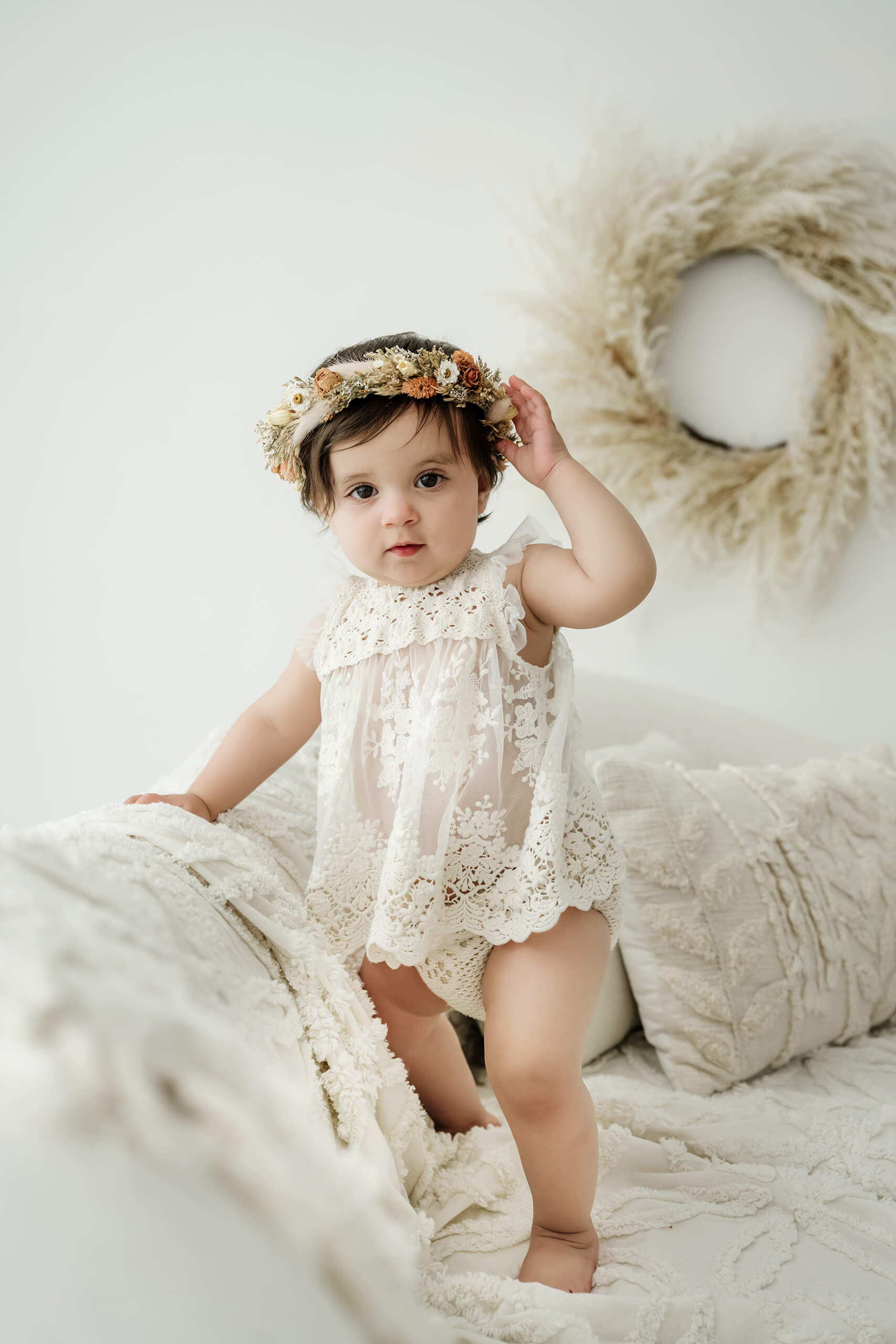 One-year-old girl standing on a white studio sofa during a Seattle first birthday milestone photography session.