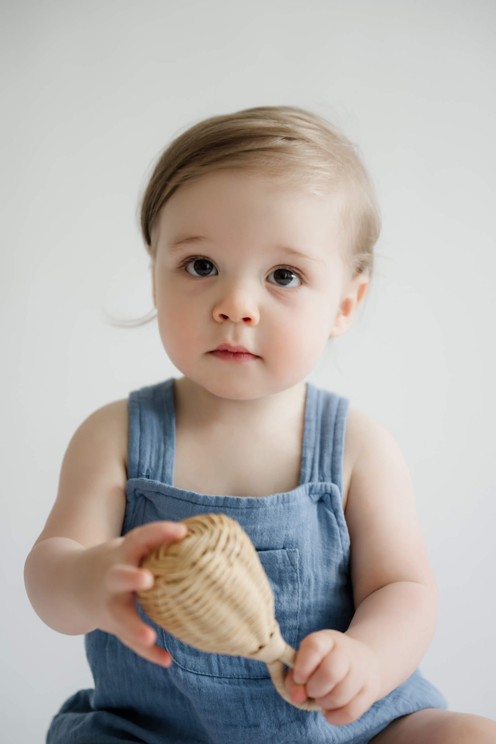 Close-up portrait of a one-year-old holding a woven toy during a Kirkland milestone photo session.