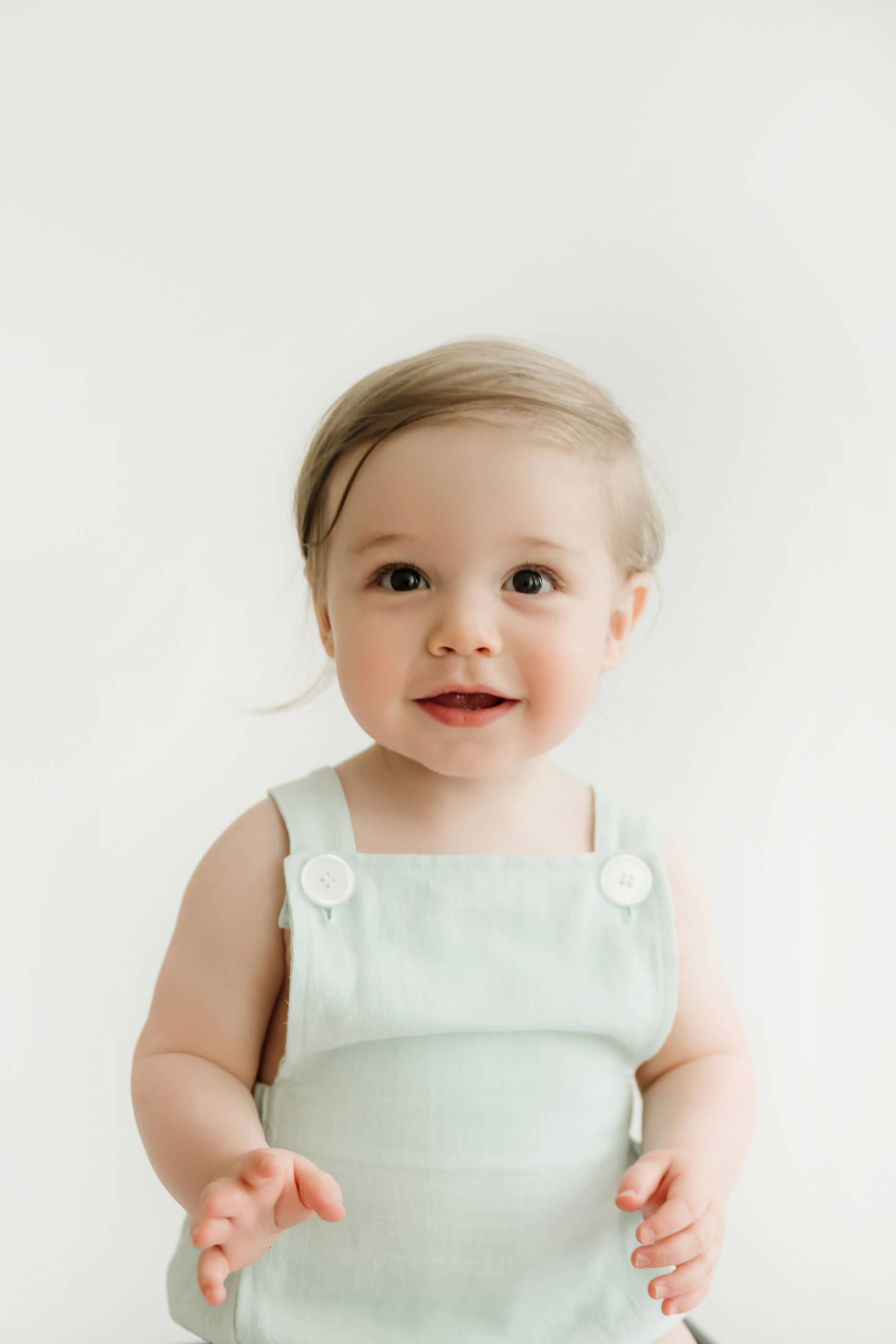 Smiling one-year-old in a pale green outfit during a first birthday milestone photo session near Seattle.