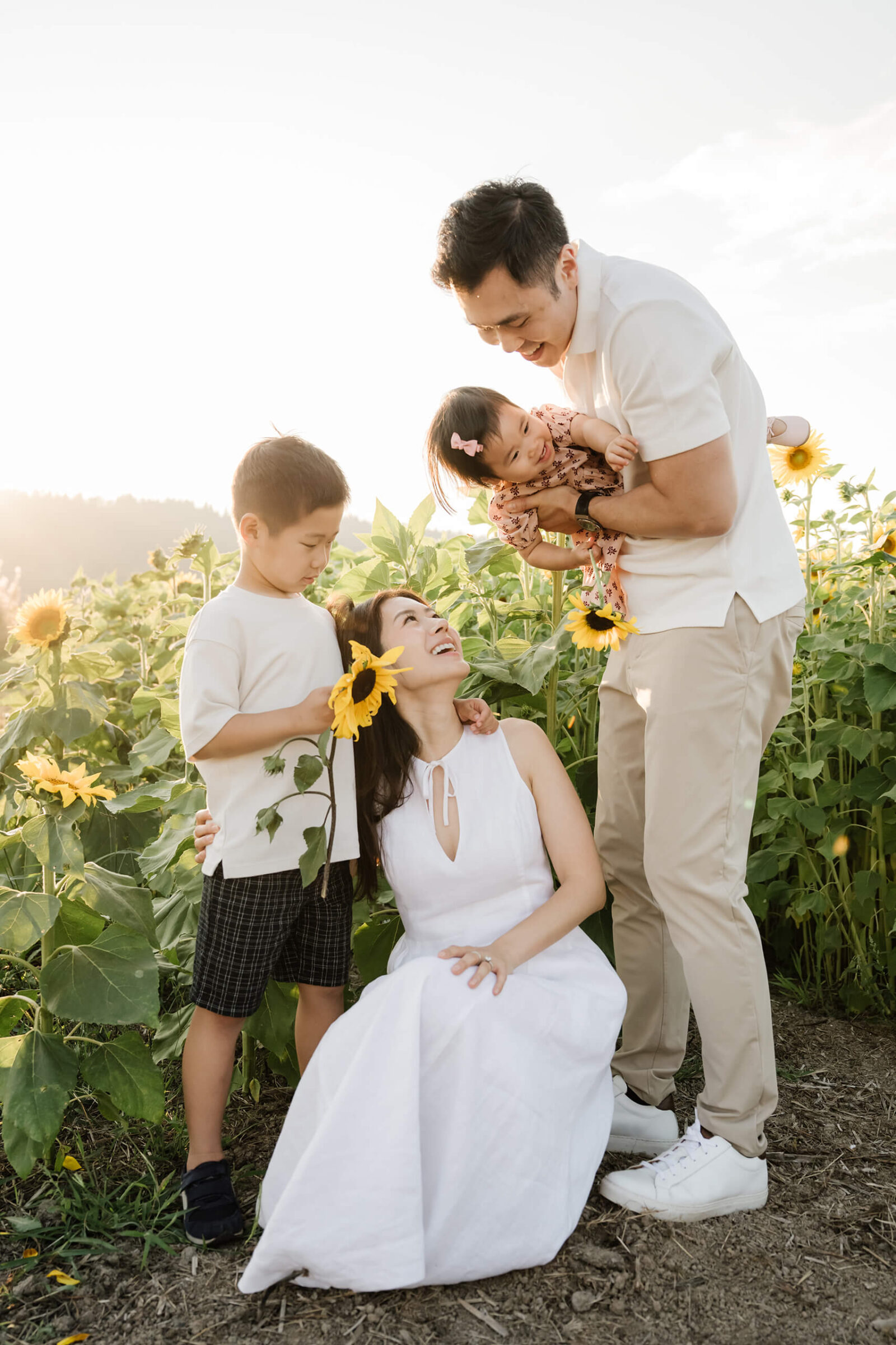 Family of four laughing together among tall sunflowers during a summer photo session in Duvall, Washington.
