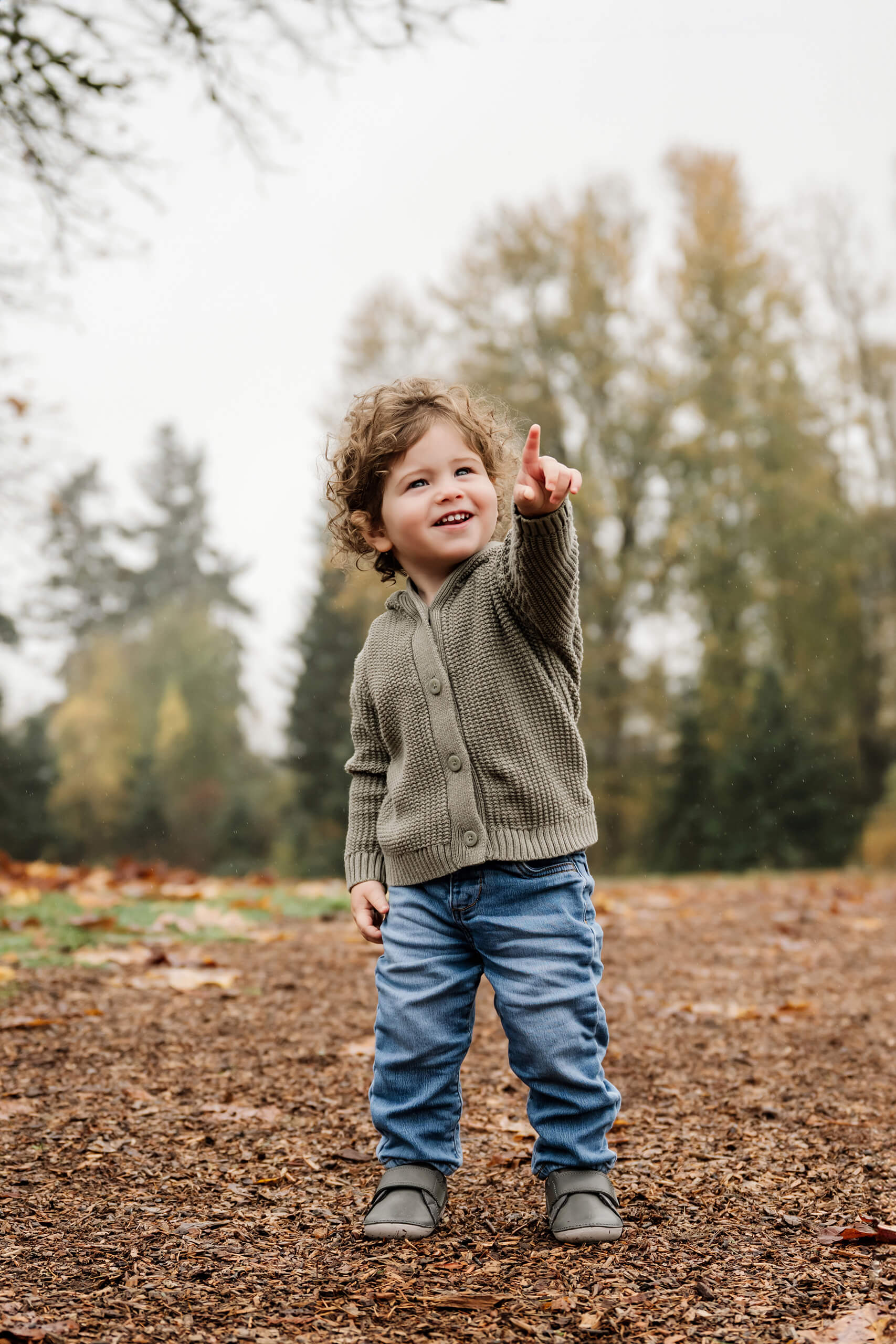 Young boy points upward while standing on a leaf-strewn path at Juanita Bay Park in Kirkland.